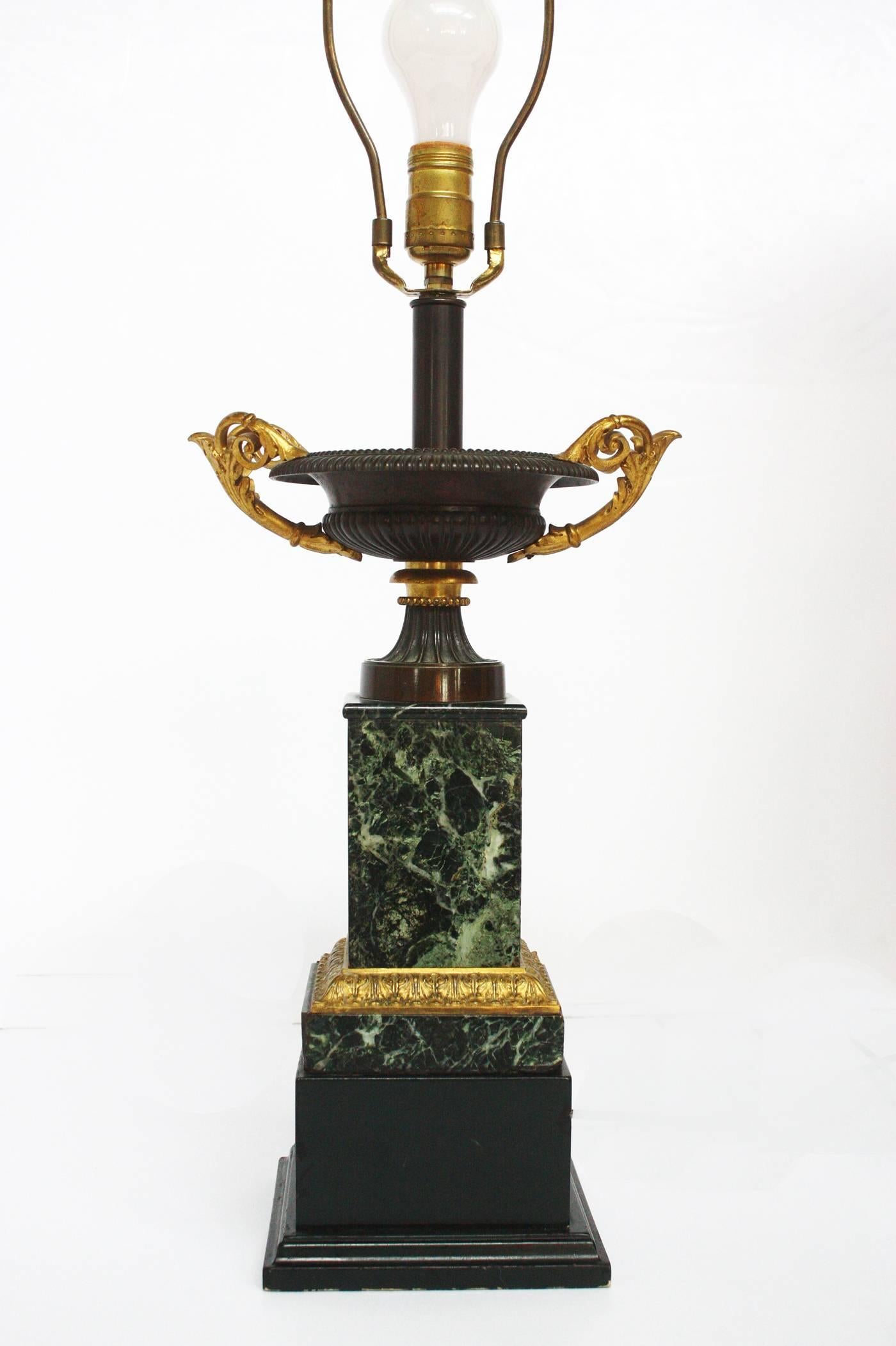 A pair of grand tour bronze tazas with gilt bronze handles on marble and wood bases accented with gilt bronze decoration mounted as lamps. Mid-19th century, France.