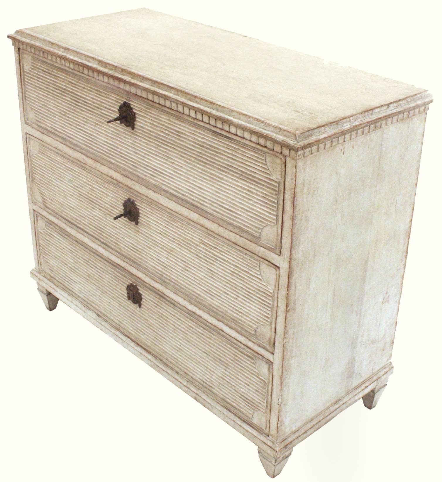 An attractive and decorative Gustavian style chest, with three horizontal reeded drawers and brass hardware, dentil molding and square tapered feet. The piece has a lovely white patina. Two keys. Swedish, circa 1860.