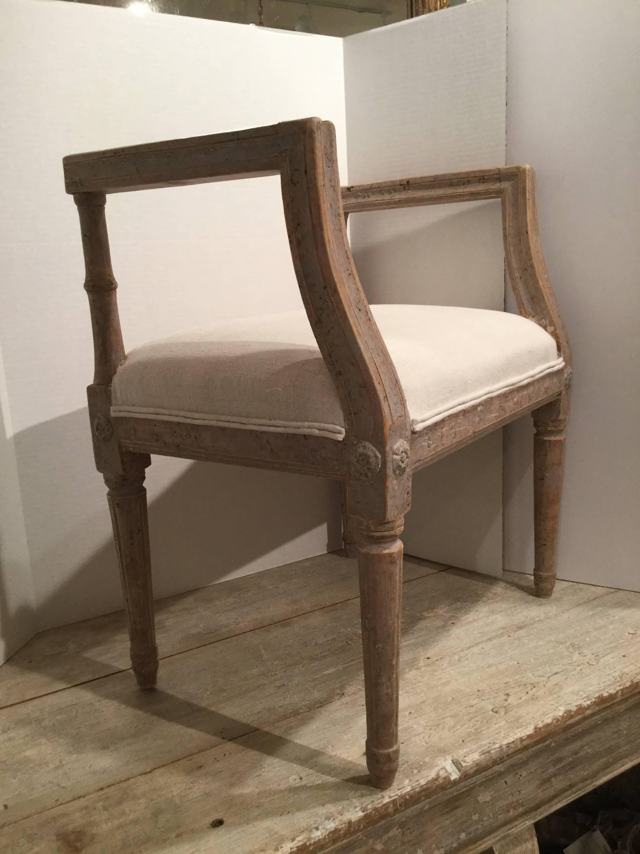 Period late 18th century Gustavian stool in original paint patina. The arms and legs have beautiful carved detail. Recently, upholstered in antique French white linen.