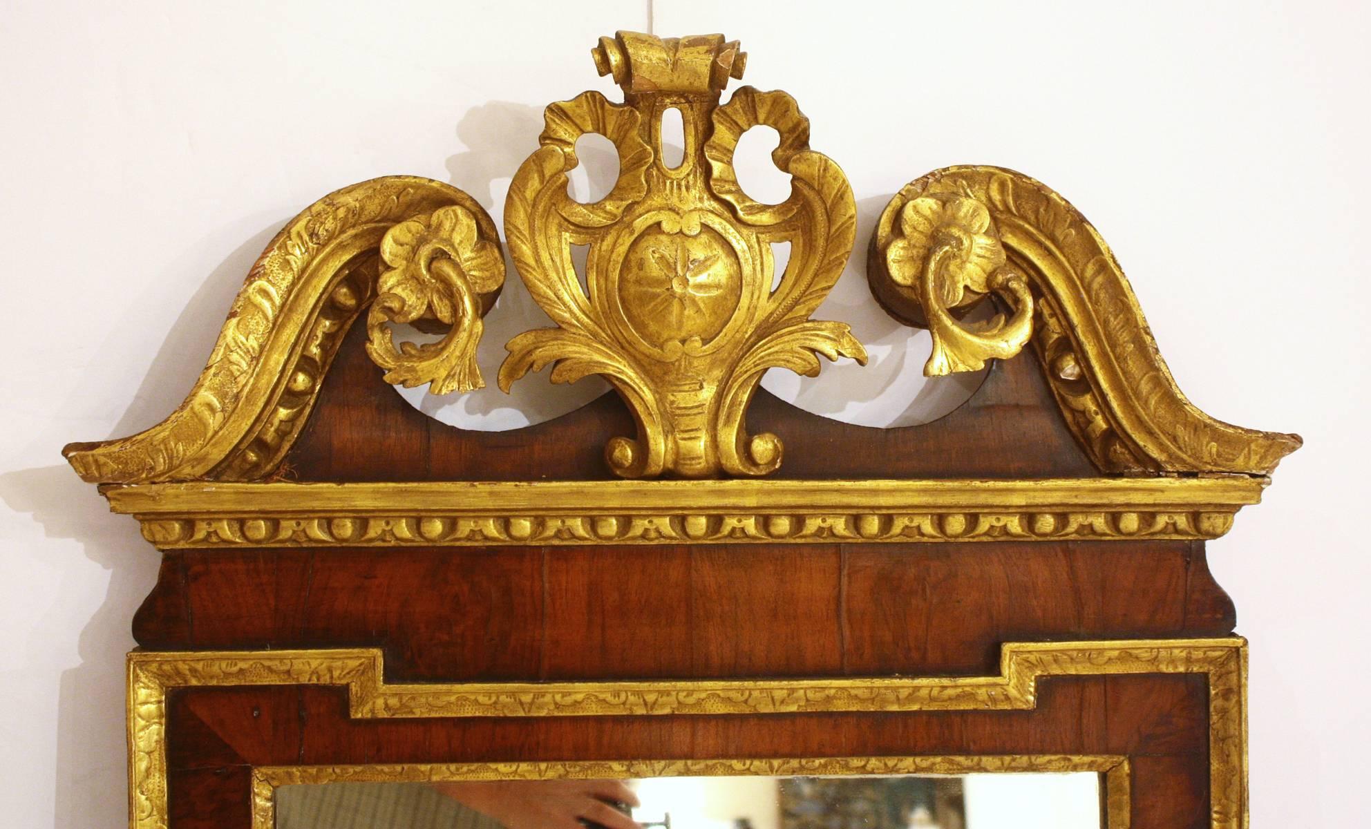 Handsome George II mirror frame of mahogany veneers with carved and gilded wood. Scrolled broken pediment with centre crest, England, mid-18th century.