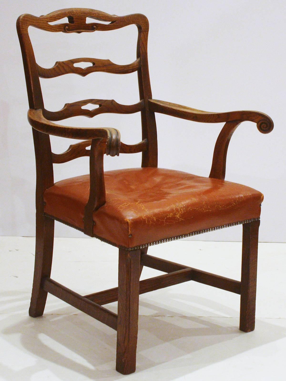 an English host / armchair with pierced rung ladderback and straight Marlborough legs (H-stretcher), British tan saddle leather seat upholstered over the rail with nailhead trim, probably made of elm, walnut colored, country Chippendale-style chair