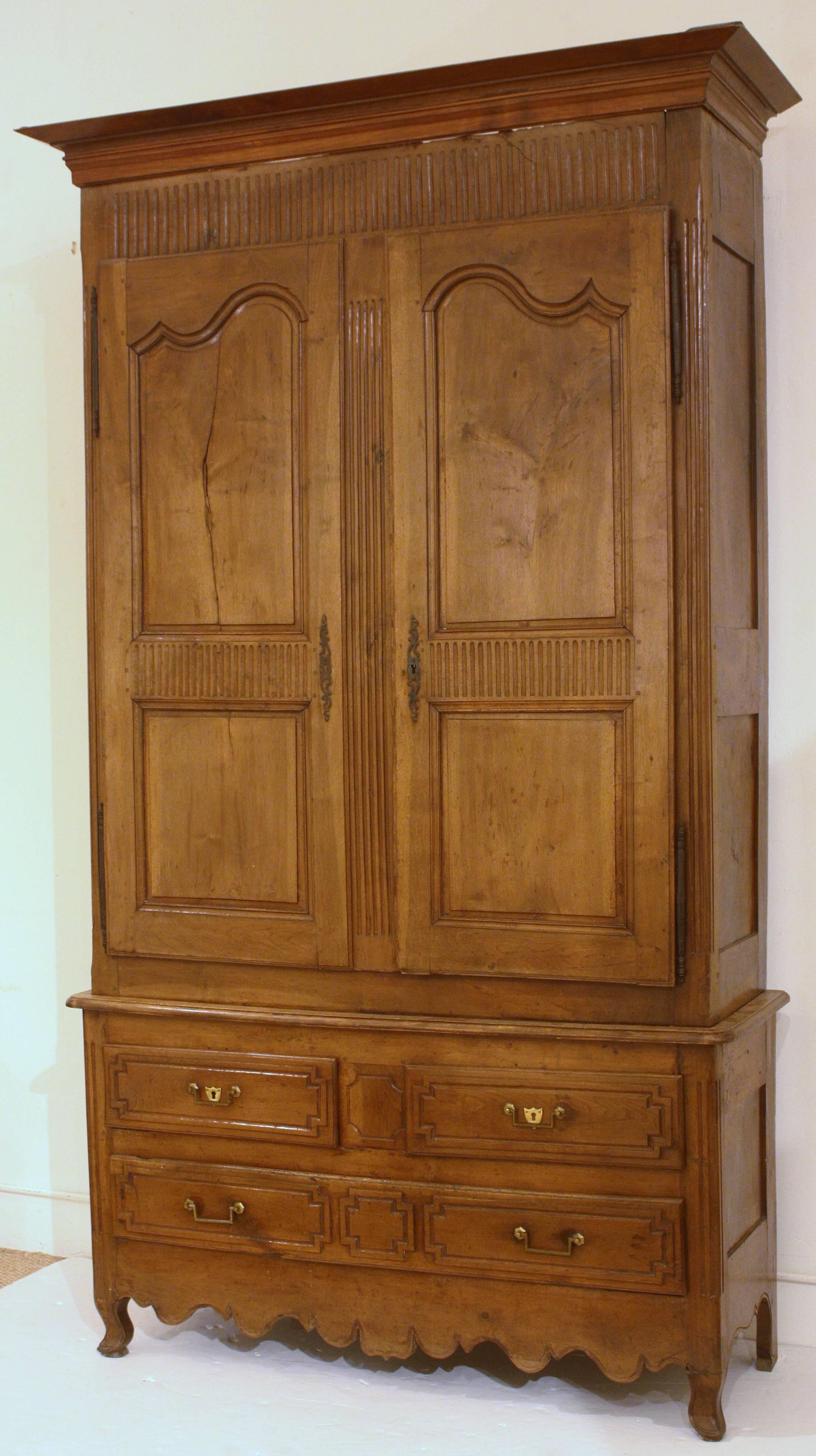Beautifully carved Provencial Louis XV walnut armoire with elegant grooves in the cornice, center stile and also central to the upper door panels. Three (3) drawers in the base have a distinctive Directoire design. A great storage piece for a