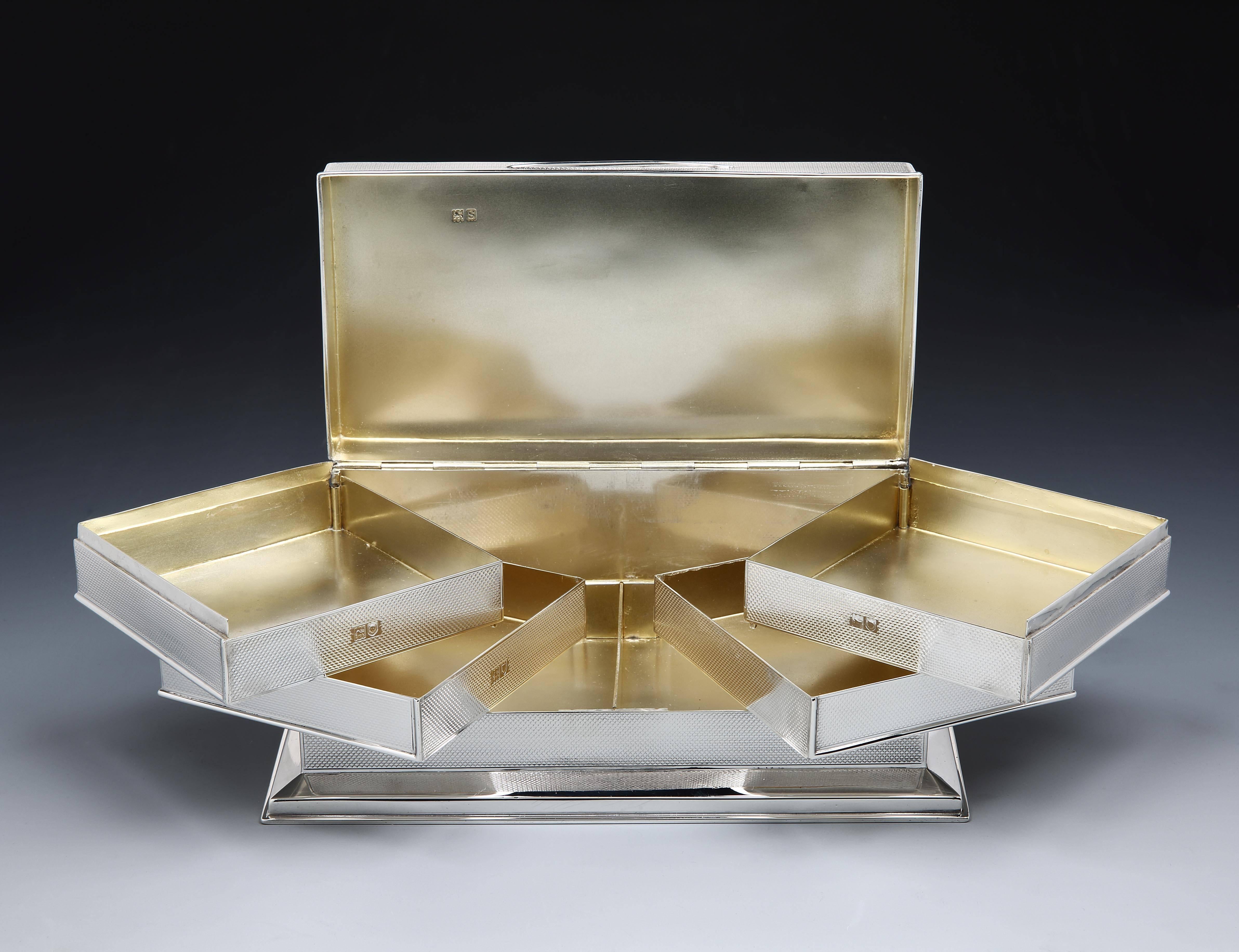 An unusually modernist-style, sterling silver cigarette or trinket box, the engine-turned body opening to reveal four lemon gilded compartments, hinged to allow them to ‘fan’ out. Hallmarked London, 1913. 

Makers marks are rubbed and indistinct but