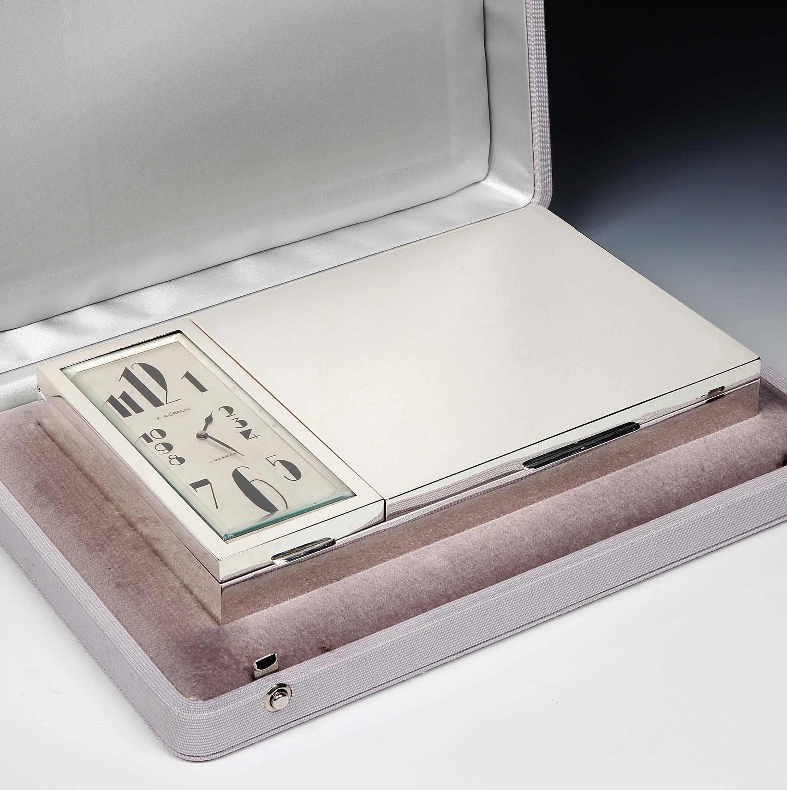 Gübelin of Lucerne, Switzerland, an extremely stylish Art Deco silver-plated cigarette box, with two hinged lids revealing compartments for cigarettes or cigarillos, and to the left, a fitted clock with Art Deco numerals and mechanical 8 day