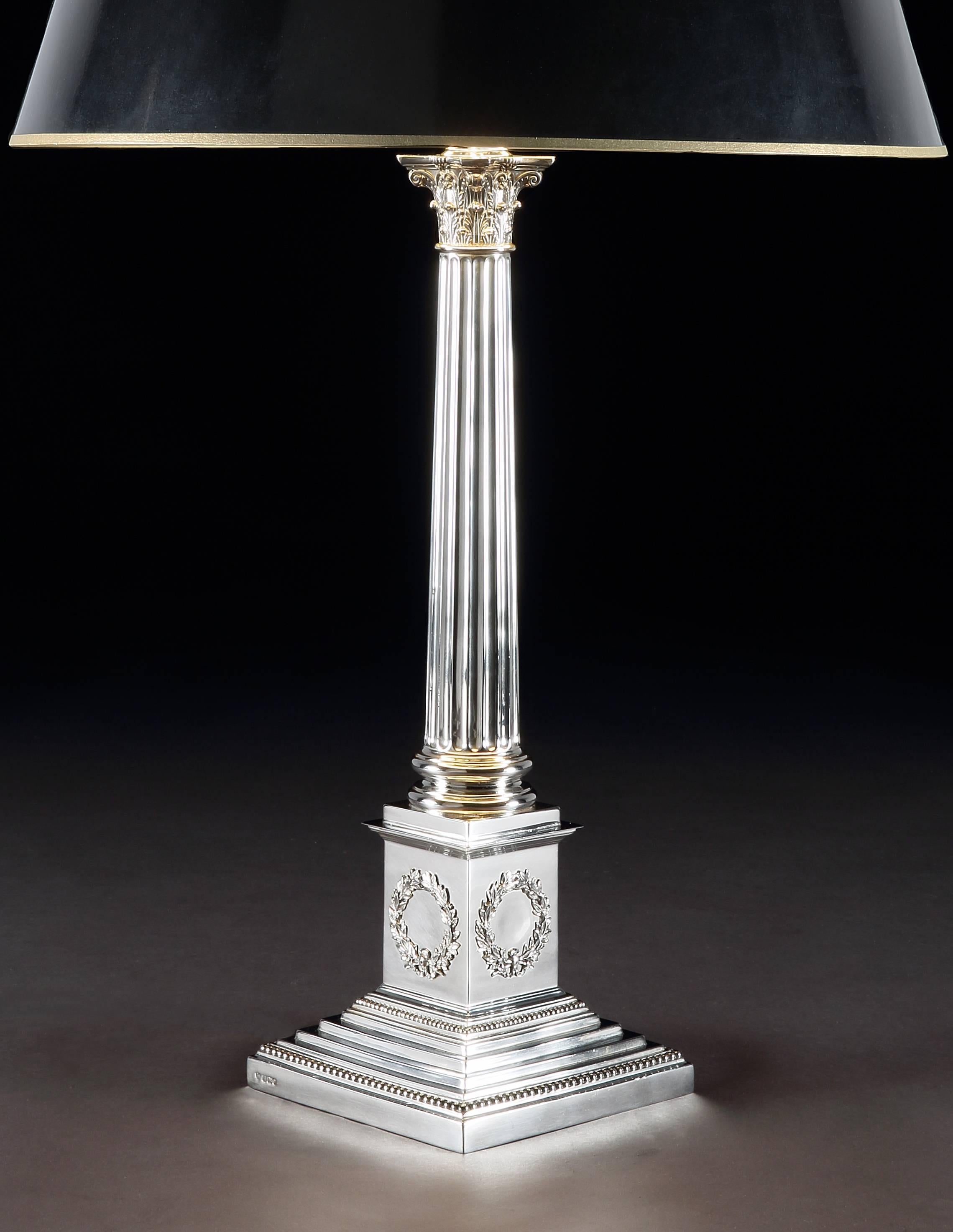 A large and architecturally grand sterling silver table lamp in the form of a Corinthian column, with a tapered reeded stem and decoration of scrolled acanthus leaves to the capital and wreathes applied to each side of the square base. Hallmarked