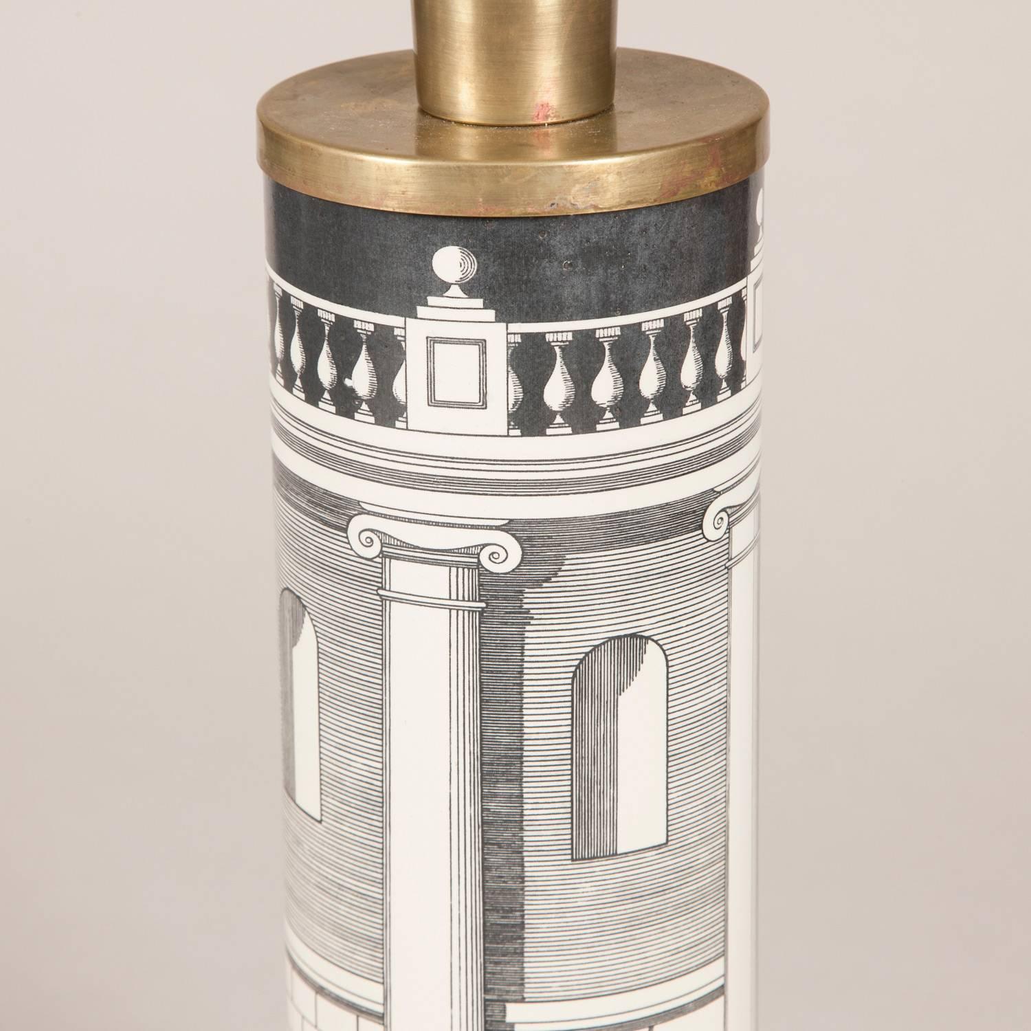 A pair of cylindrical table lamps designed by Fornasetti with architectural decoration and brass mounts, mid-20th century.