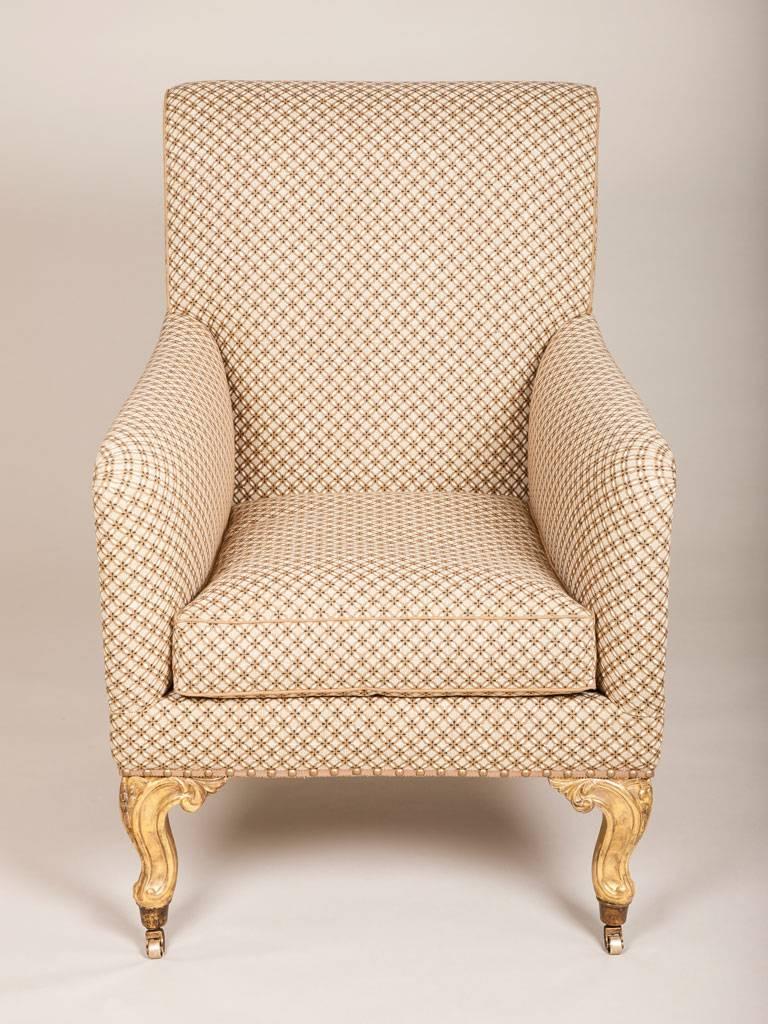 A late Regency armchair with an overscrolled back and carved and gilded cabriole legs.