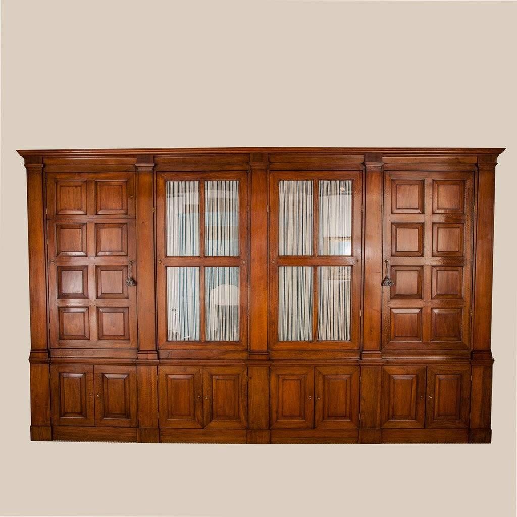 A large Italian walnut bookcase in four sections, the upper part with two glazed doors between square-panelled doors separated by pilasters, enclosing drawers and shelves, circa 1840.