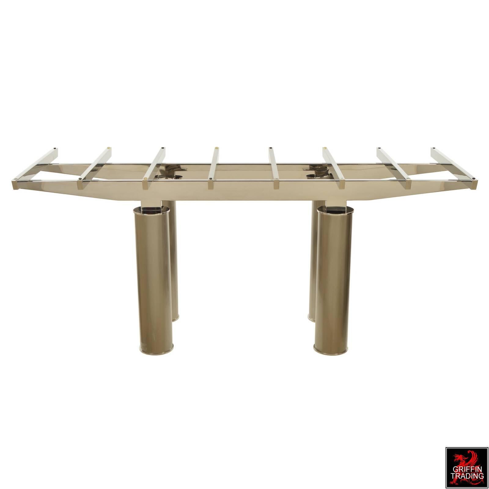 This elegant dining table has an impressive structural design in chrome, that rest on four large pillar legs in brushed metal. The large glass tabletop and striking combination of metals adds to the tables distinctive appearance. The table was