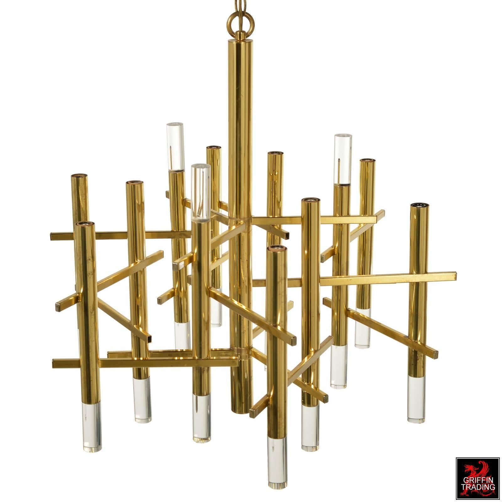 This striking brass and Lucite chandelier is by Italian designer Gaetano Sciolari. The chandelier has an elegant structural appearance, which is created by the horizontal brass rectangular tubes in a staggered configuration, connecting the 12 large