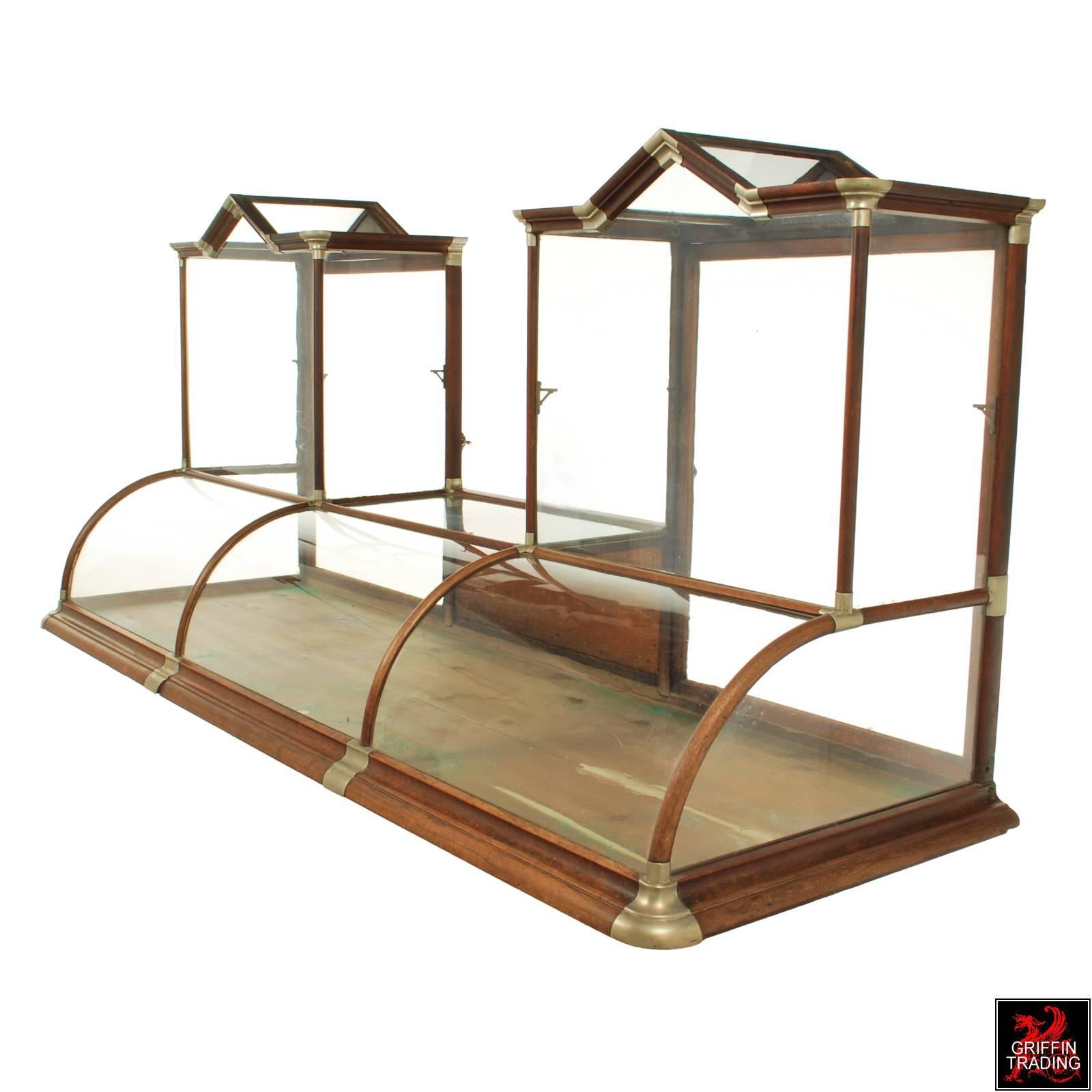 Here is a beautiful antique curved glass and oak display cabinet from the late 19th-early 20th century. This handsome store fixture is especially nice because its flanked on each end with a taller shelf area that is topped with a gable roof,
