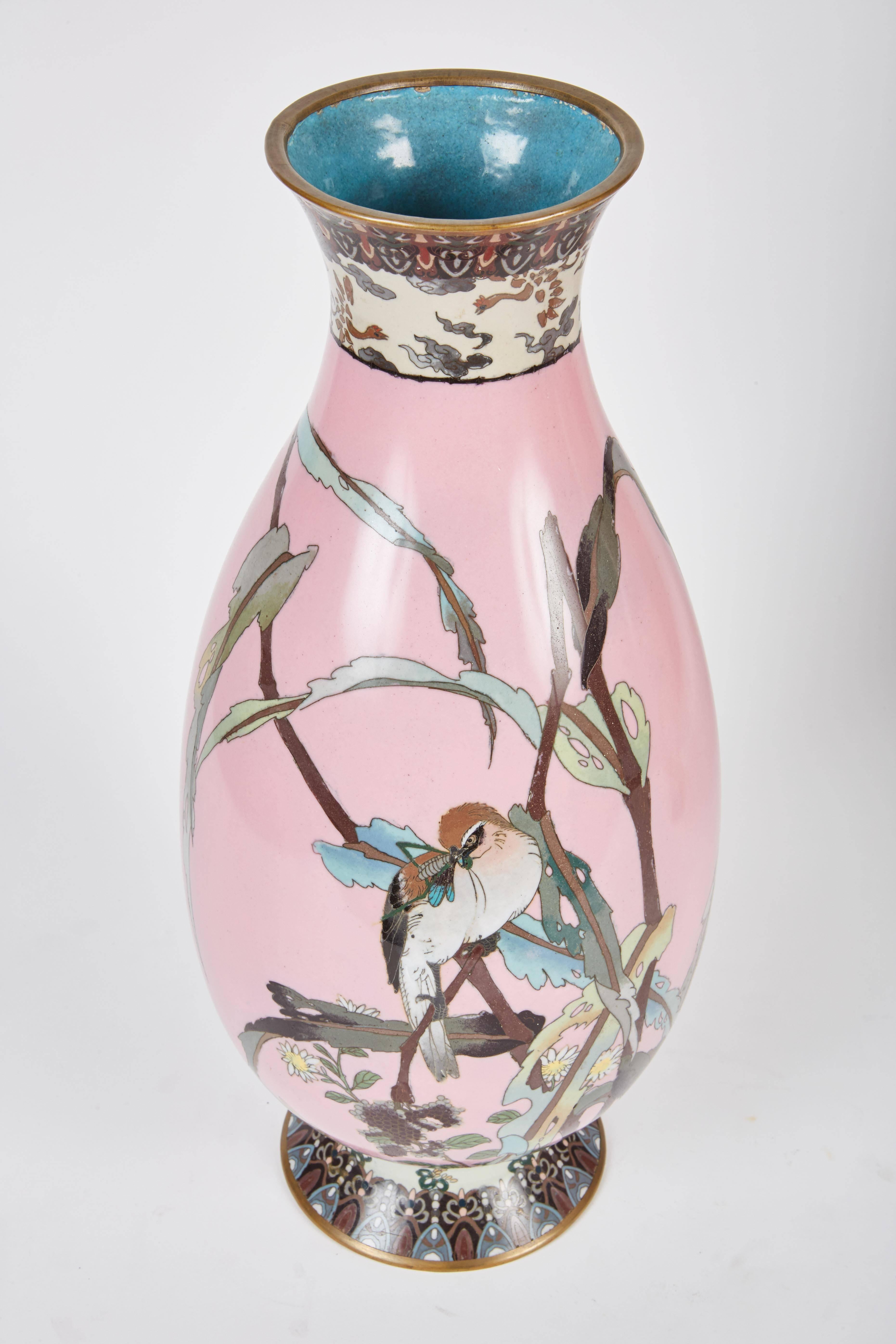 A pair of magnificently detailed pastel pink Cloisonné vases from late 19th century Japan, with depictions of birds resting on tree branches in a pink field.