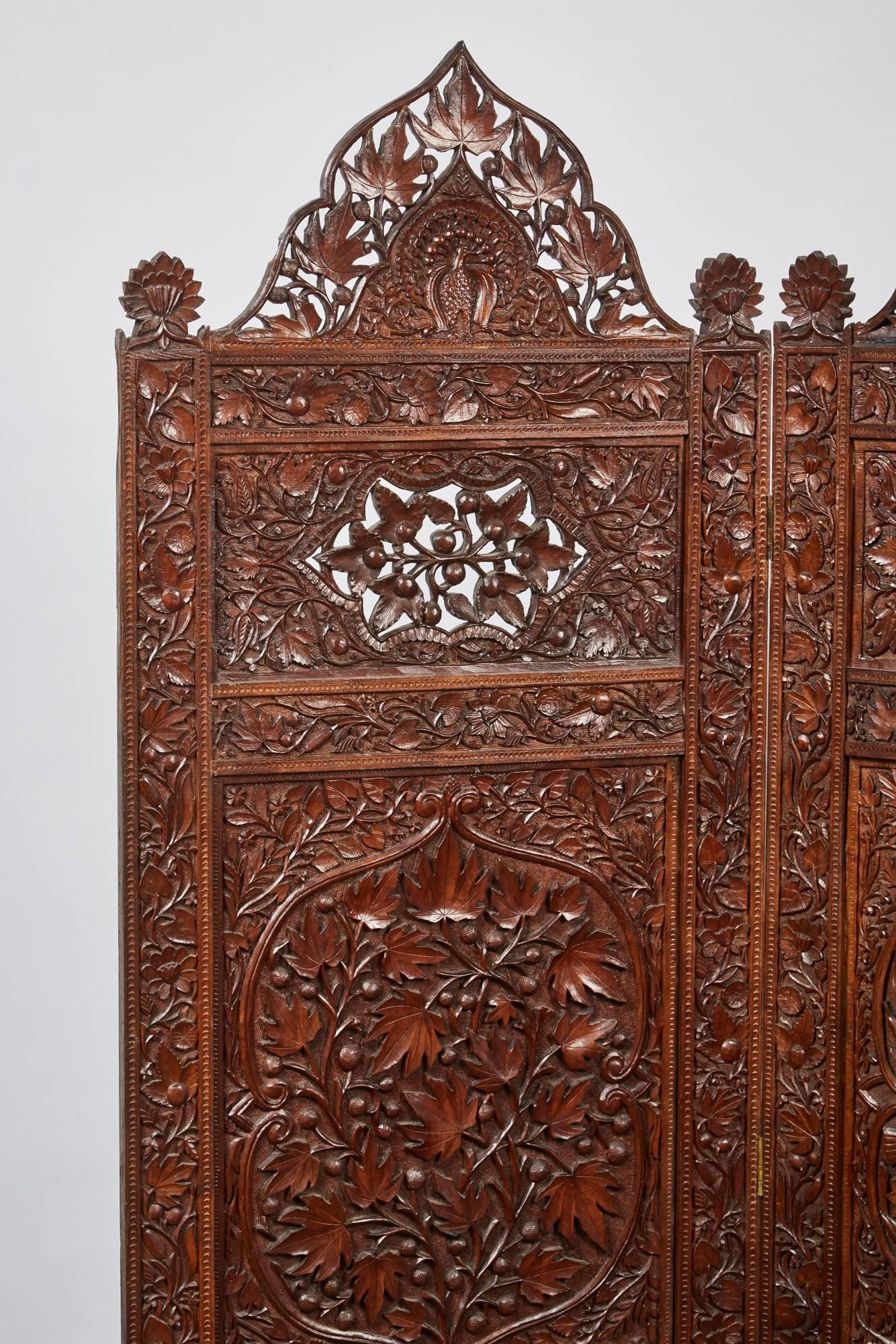 A stunning three-panel Indian screen with elaborate and decorative carvings of foliage design. Each panel has a beautifully carved peacock in the top pediment.