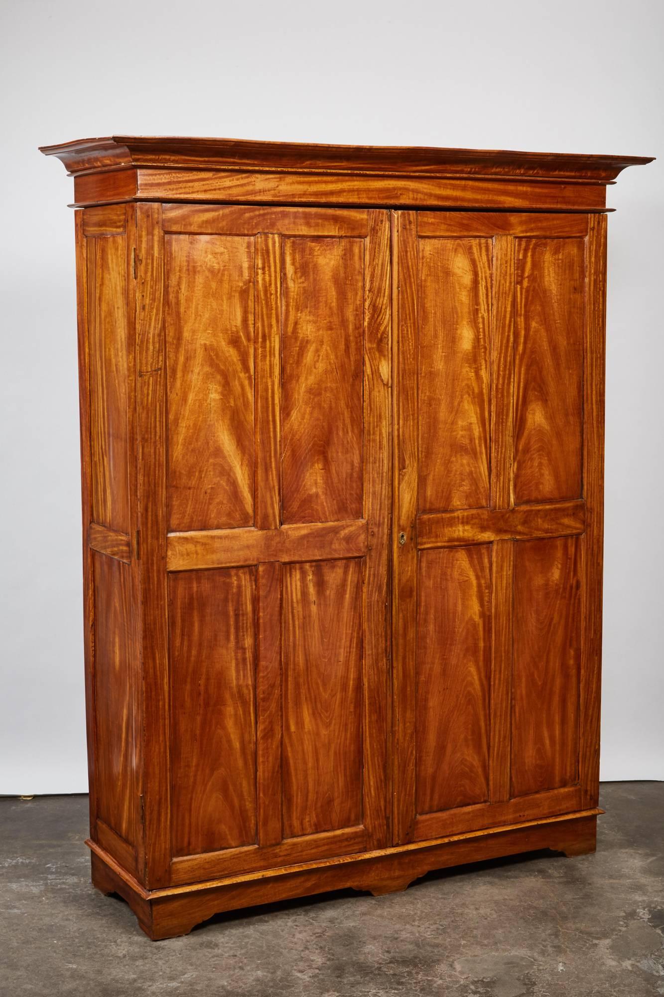 This simple yet elegant two-door satinwood cabinet from 19th century British Colonial Sri Lanka has a pair of eight carved wood panel doors and sits on a set of six rectangular legs.