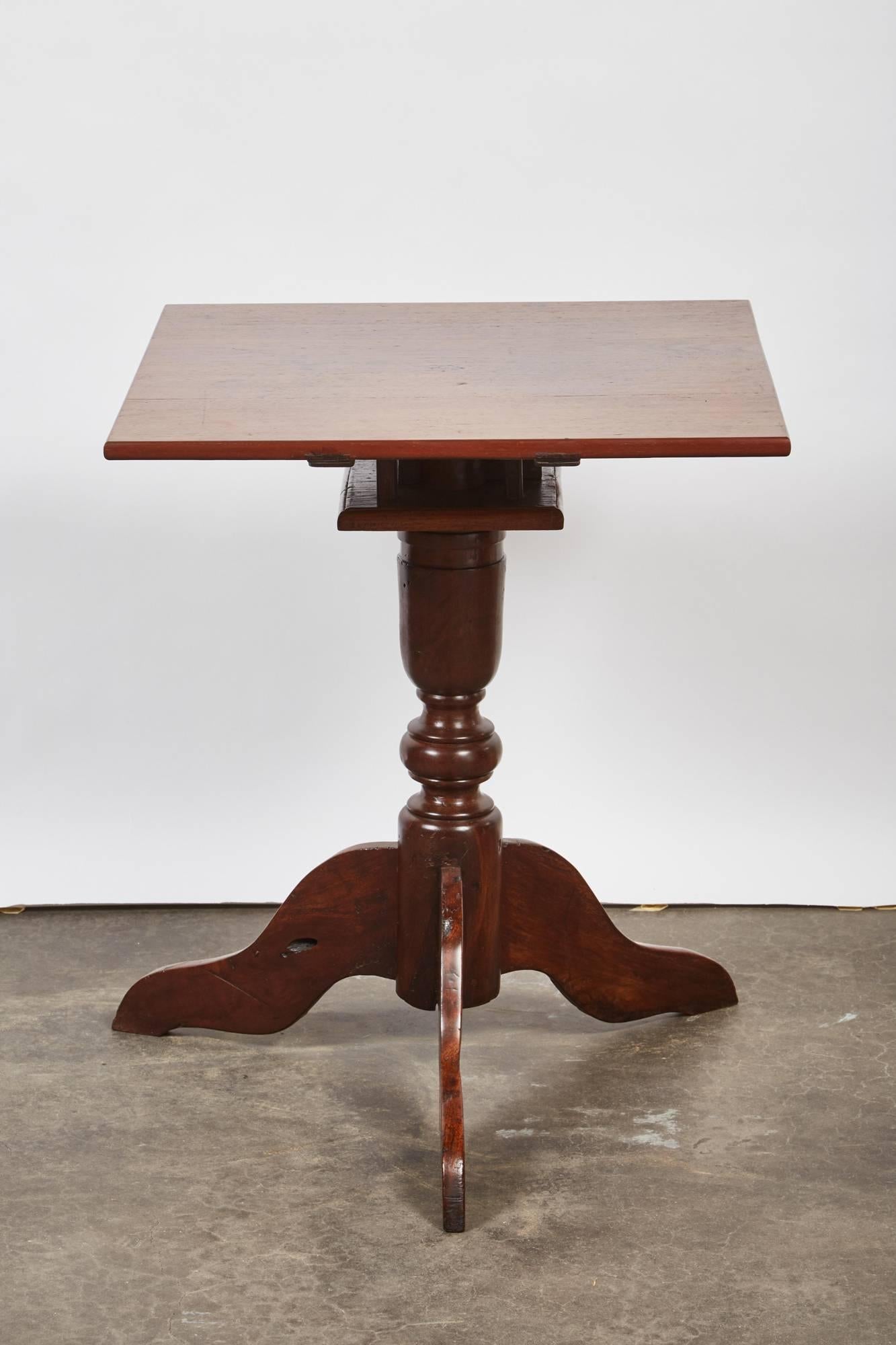 This mid-19th century tindalo wood square top pedestal table feature three snake legs with a square top.