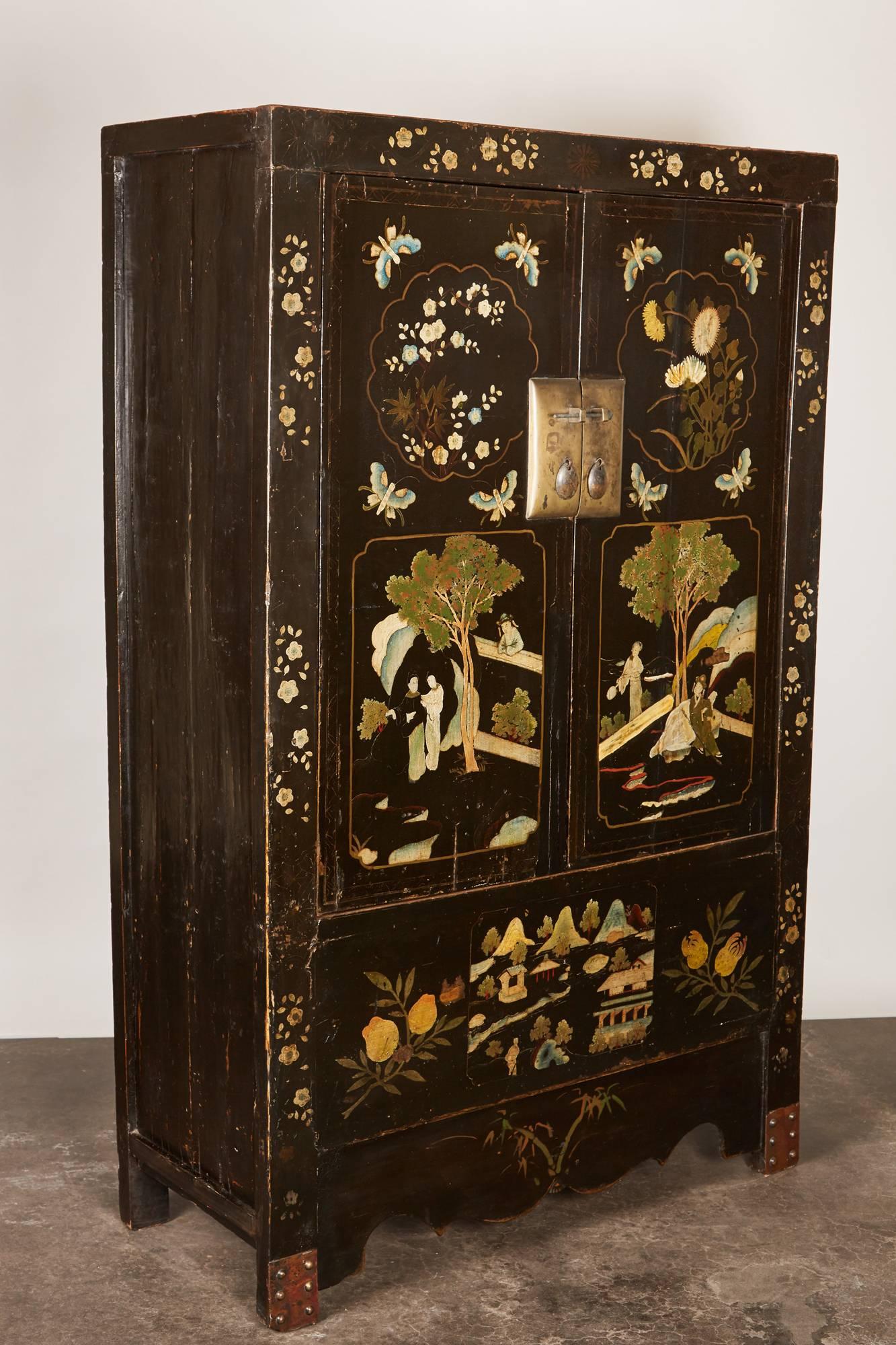 A rare pair of 18th century Chinese black painted cabinets made from traditional construction techniques. With all of its original hardware and metal studded feet, the cabinets also depict daily life while also representing the four seasons. The two