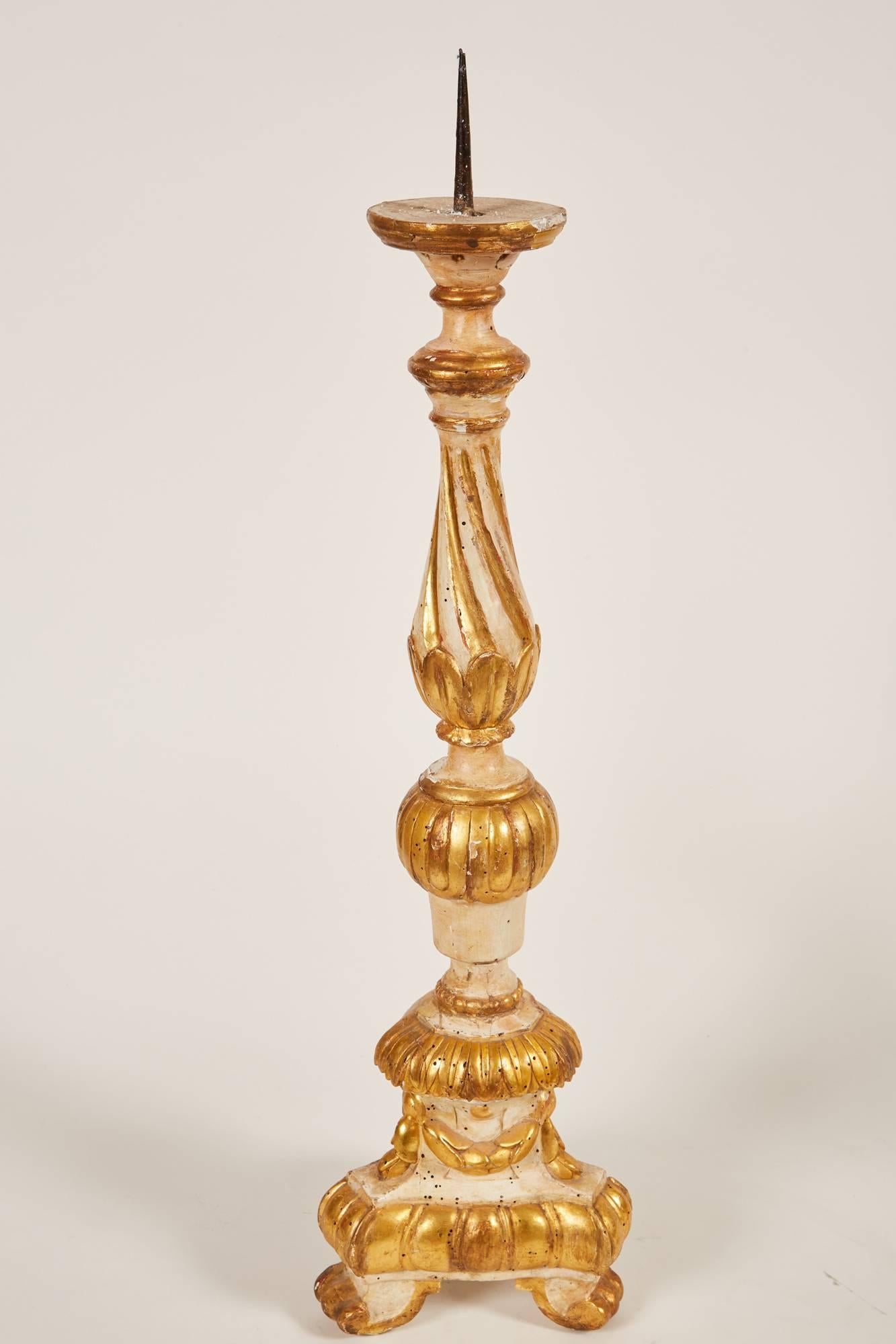 A marvelous pair of carved giltwood Italian candlesticks that feature garlands along the base right above The claw feet, as well as the acanthus leaf motif throughout the entire shaft of the candlestick.