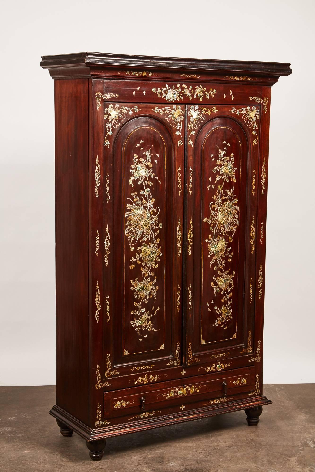 A 20th century French Colonial Vietnamese rosewood cabinet that features stunningly beautiful inlay of peonies and other foliage design in mother-of-pearl (M.O.P) across the facade of the cabinet.
