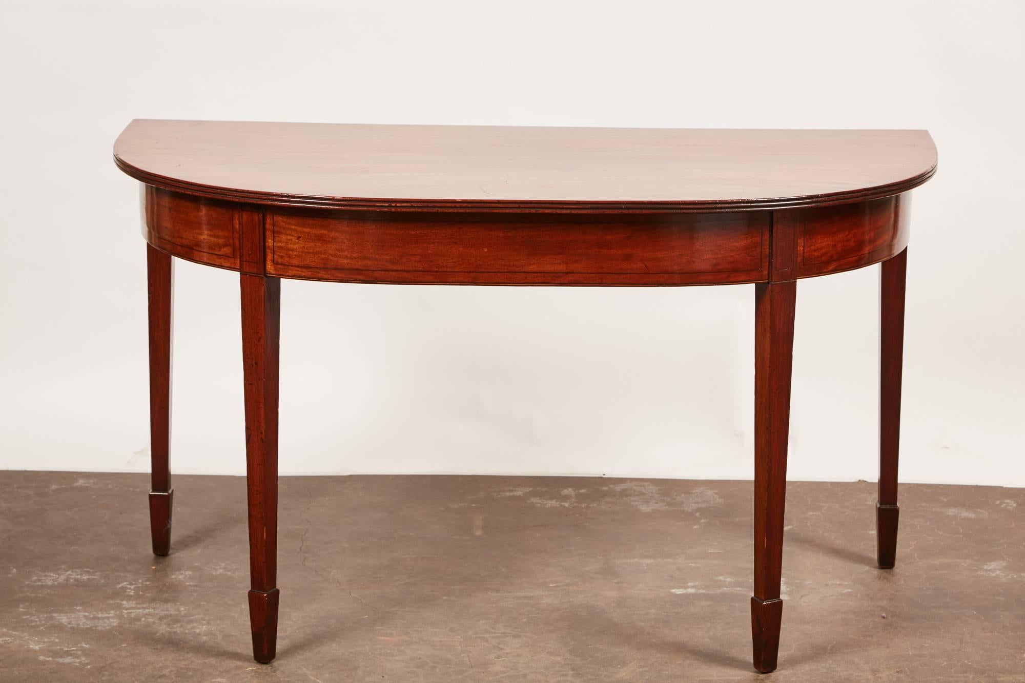 A remarkable pair of D-shaped Georgian mahogany console tables with clean and simple lines.