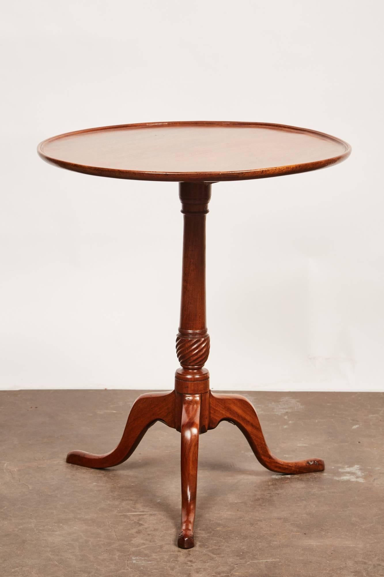 This late 18th century George III mahogany side pedestal table features a molded dished circular top above a turned and carved baluster shaft, on a set of three cabriole legs and padded feet. The top is a single piece of mahogany.