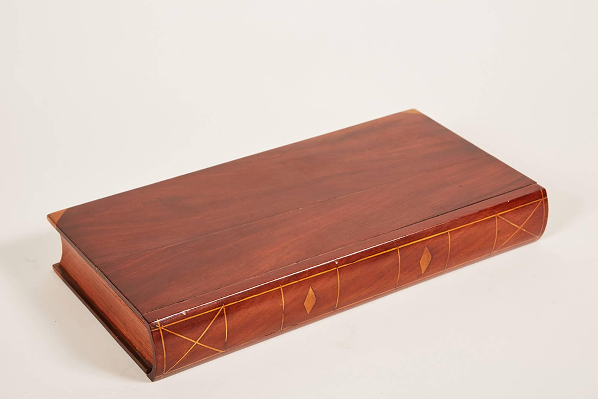A mahogany “dummy” book the front inlaid and “pages” simulated by pitch pine. The pulls open to reveal a drawer with compartments.