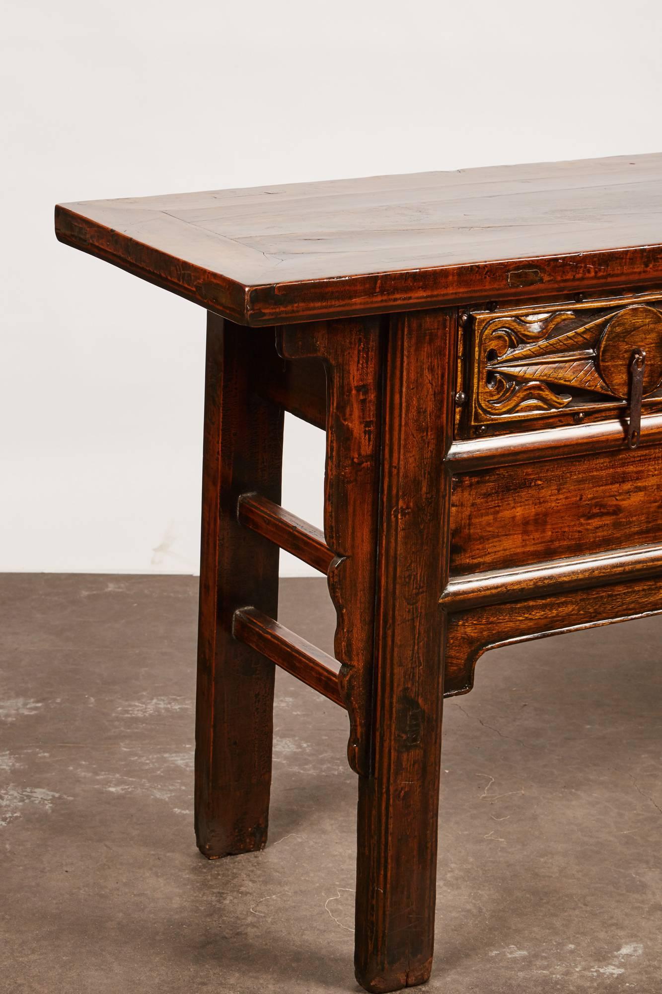 A late 18th century Mongolian elm console table that features three distinctively carved drawers. The set of three drawers are carved to portray identical abstract foliage designs with exposed nailheads along the trim.