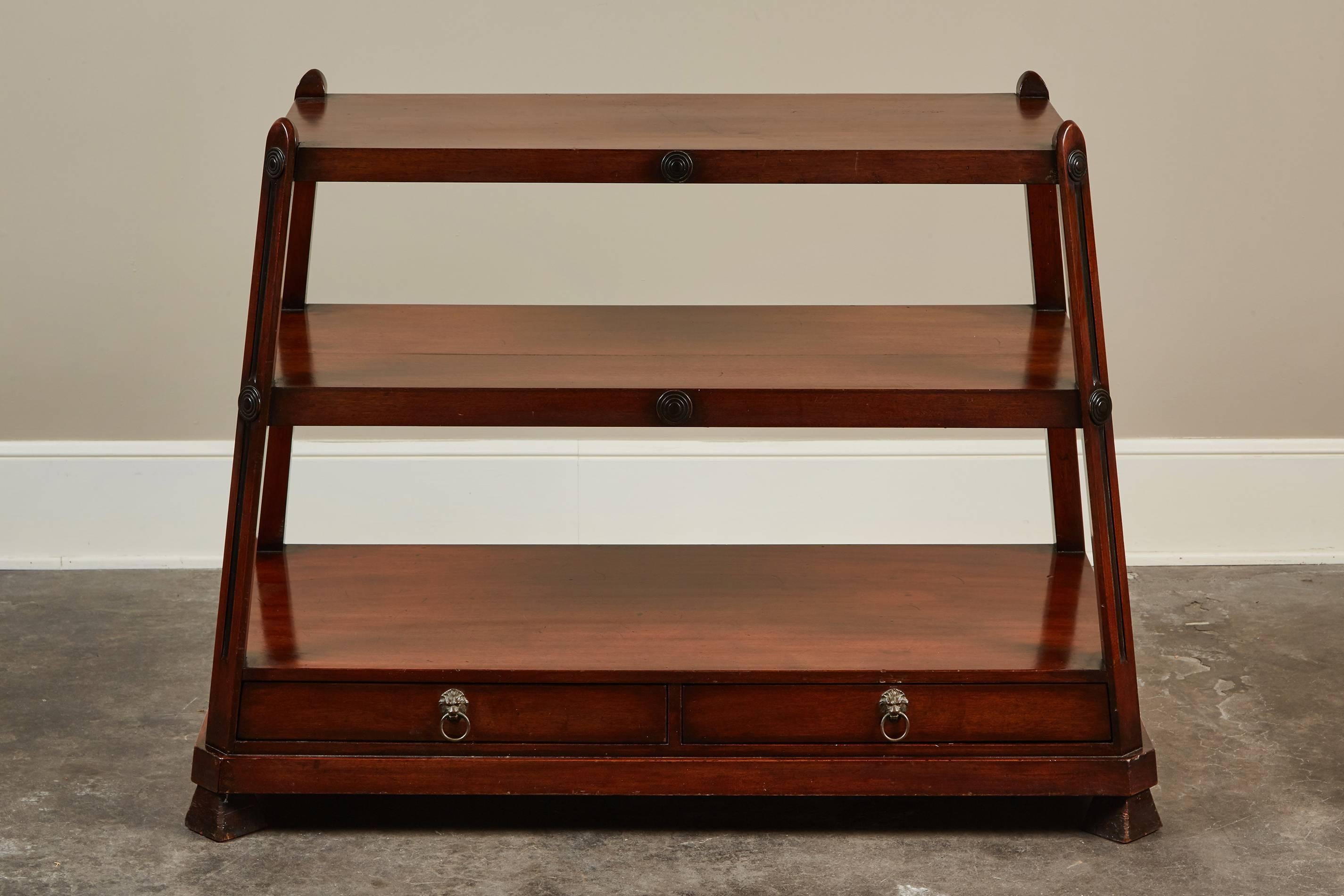 A unusual English mahogany three-tier server with two drawers. The server features slanted legs that rise up to the top and at the base there are two drawers with lion head hardware.