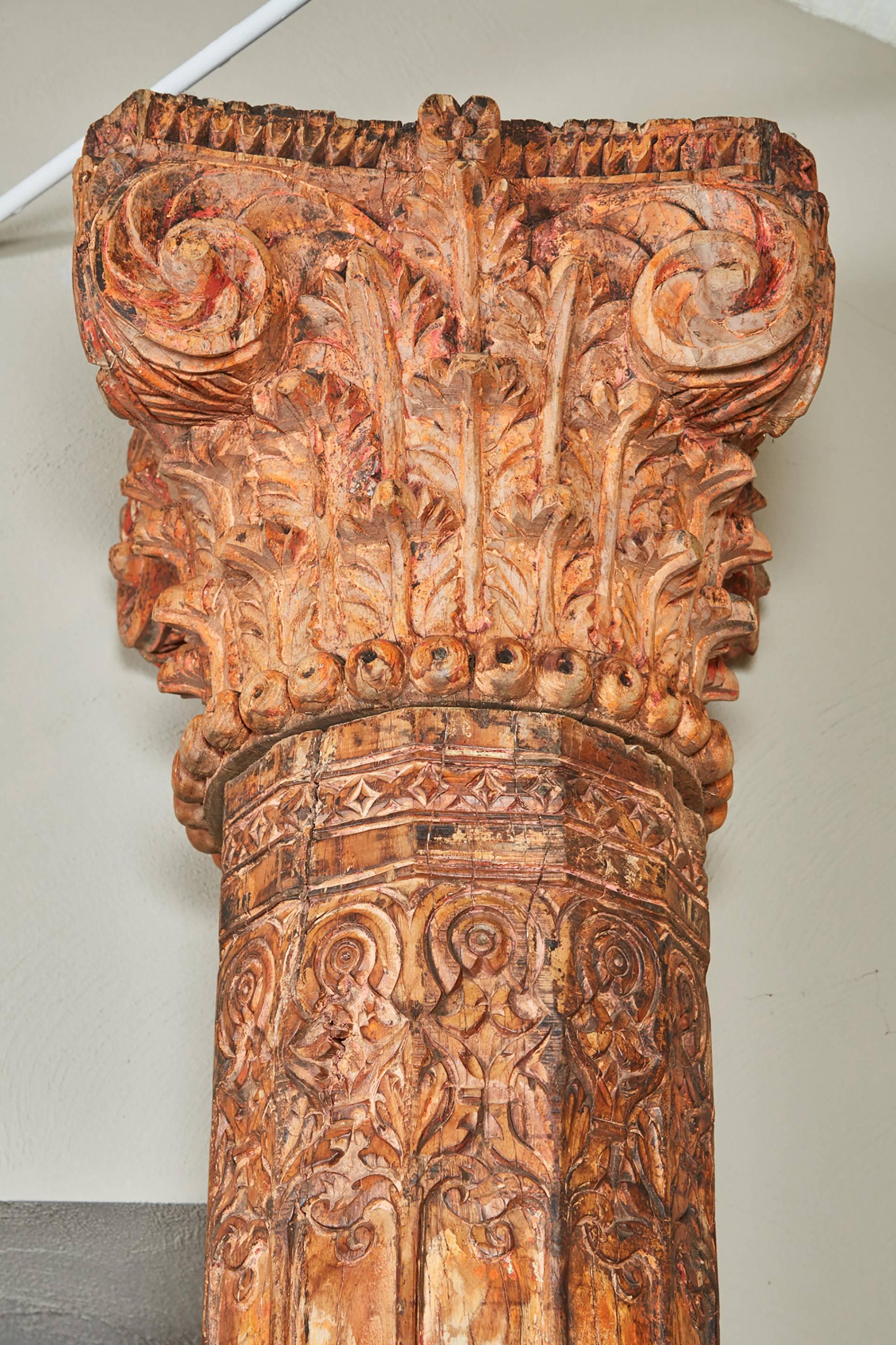 These pair of orange tall Indian teak wood pillars are topped with classical acanthus leaf capitals and come in three parts. The shaft of the column is beautifully decorated with carvings.
      