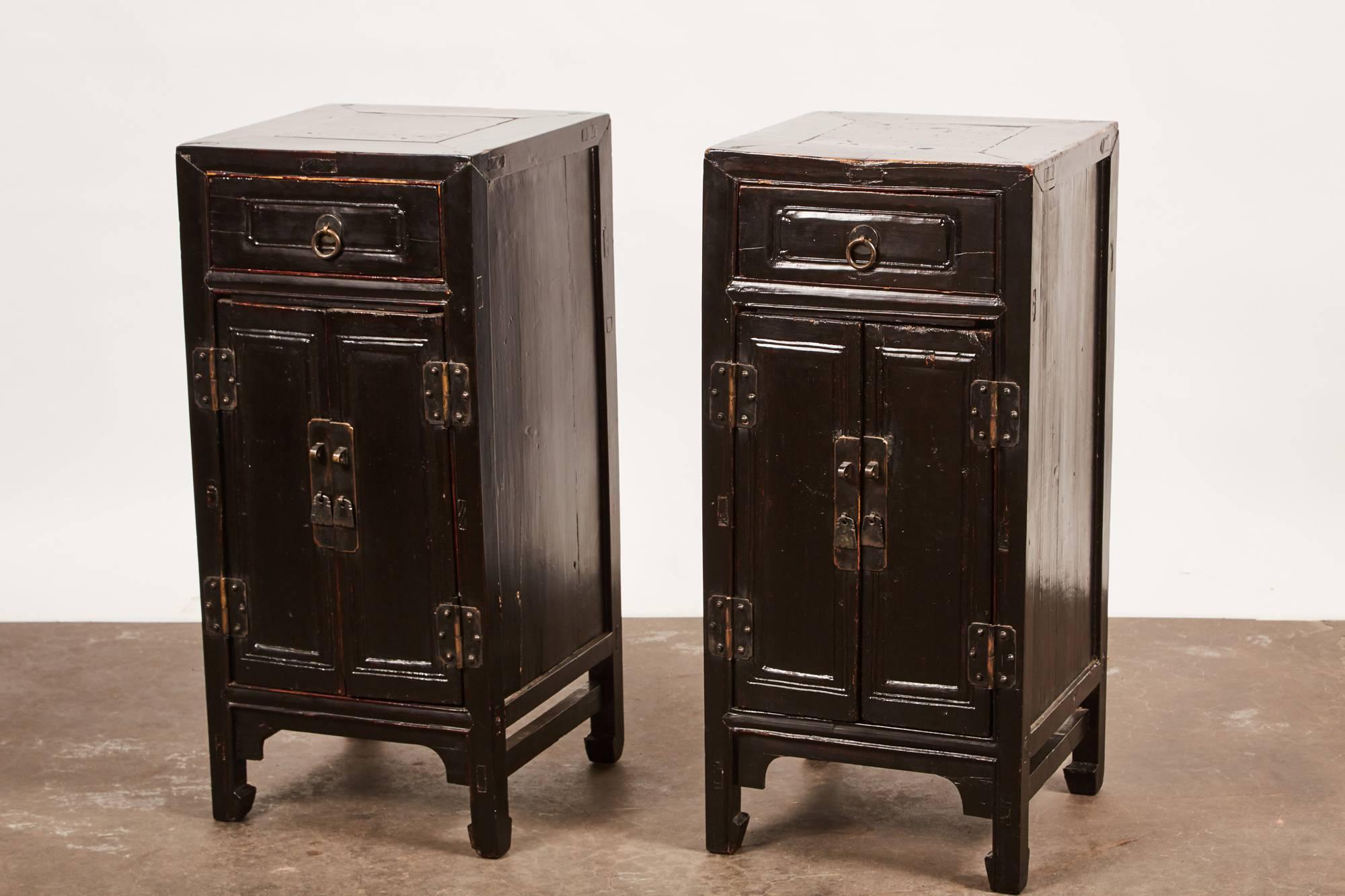 Pair of black lacquer side cabinets with a single drawer and two doors.