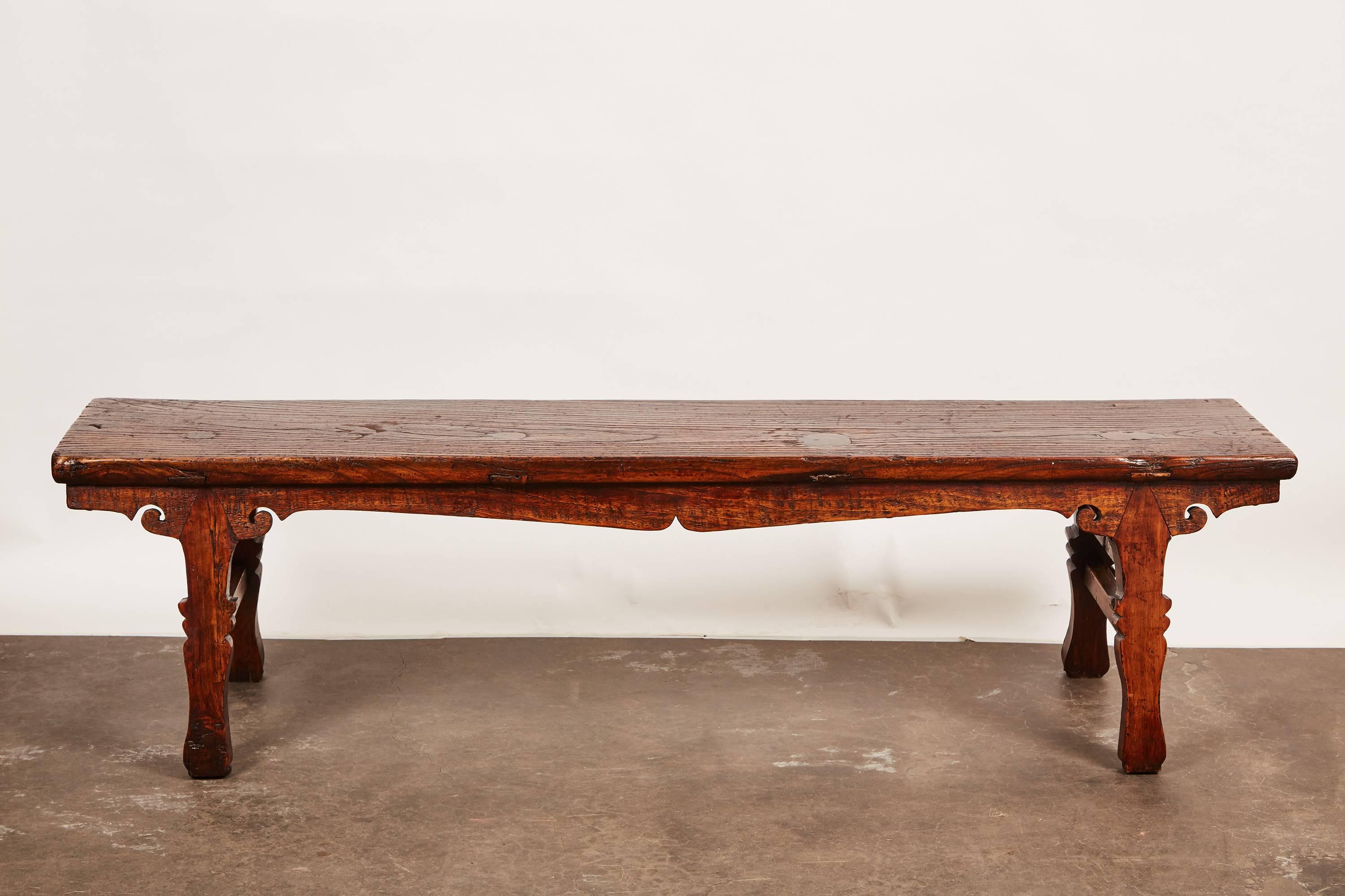 An 18th century Chinese low sword leg bench or table with intricate carvings all along the legs.