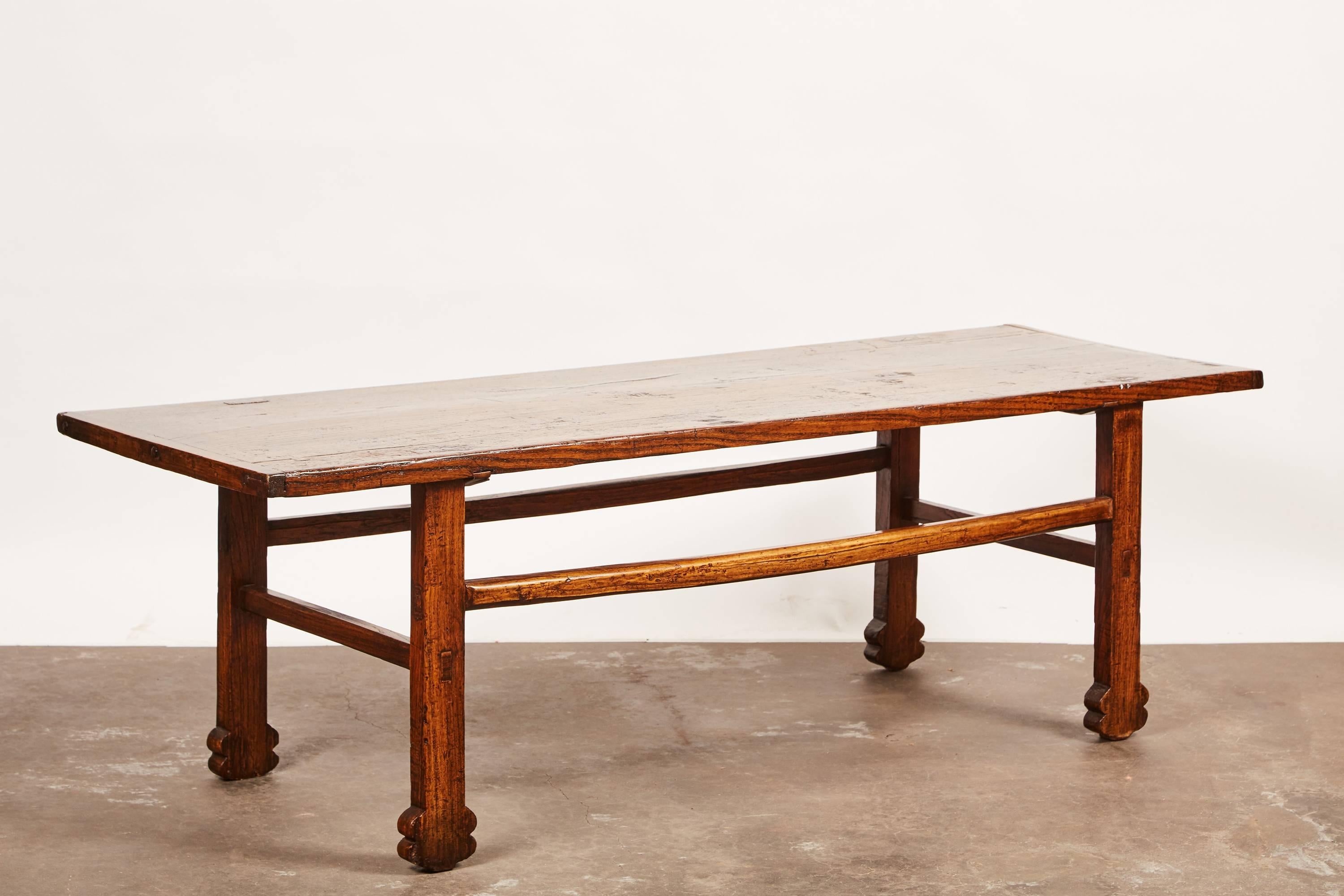 A “one of a kind” kang table - otherwise known as either a low table or a chair-level bed- with solid elmwood tabletop and plum feet. The table is originally from Shanxi, China.
