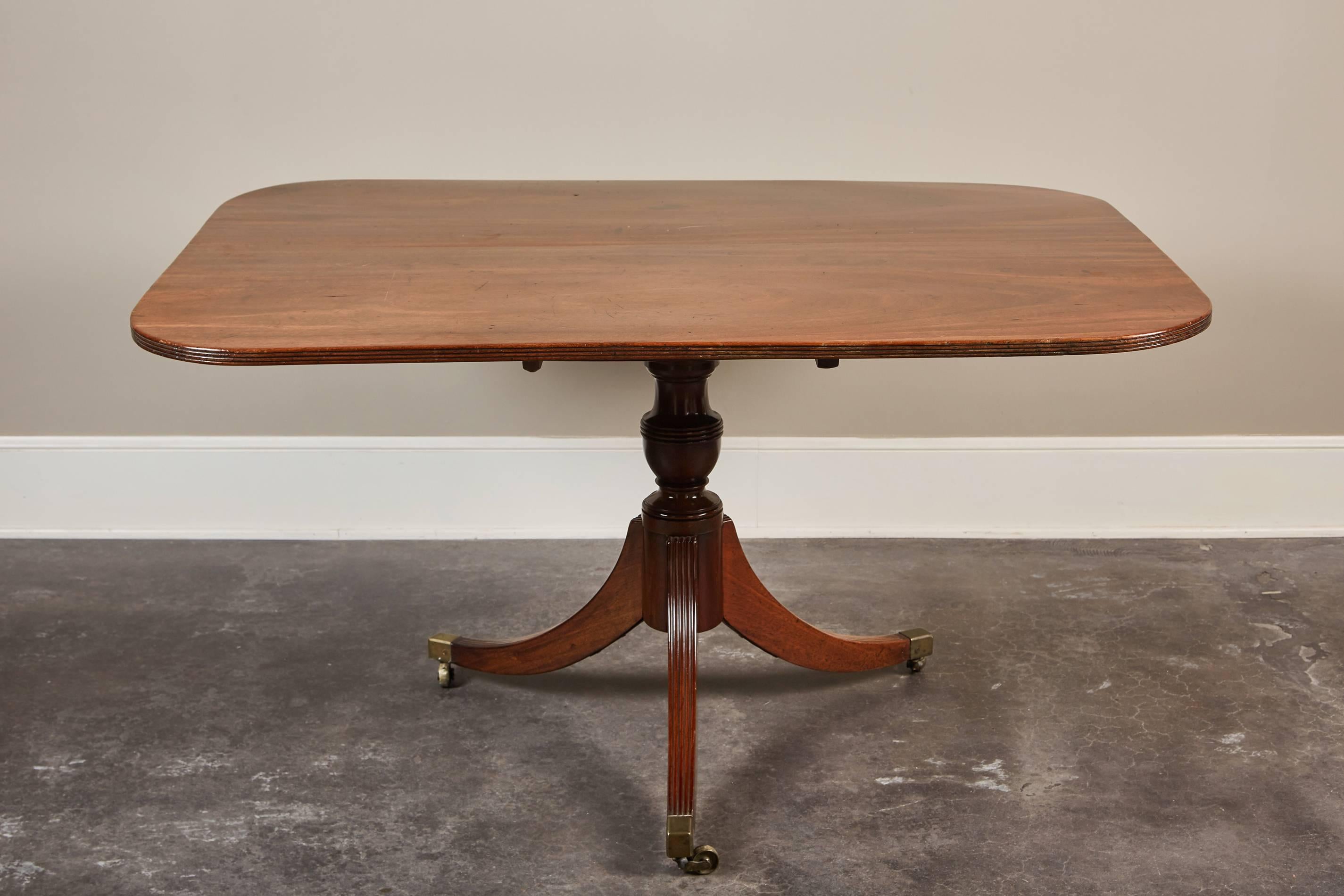 Georgian Mahogany Breakfast Pedestal Table,ca 1790. Solid Mahogany two piece book matched  tilt-top supported by a turned pedestal resting on three out swept legs on brass castor feet. Handsome patina overall with rifled edging on top and legs.