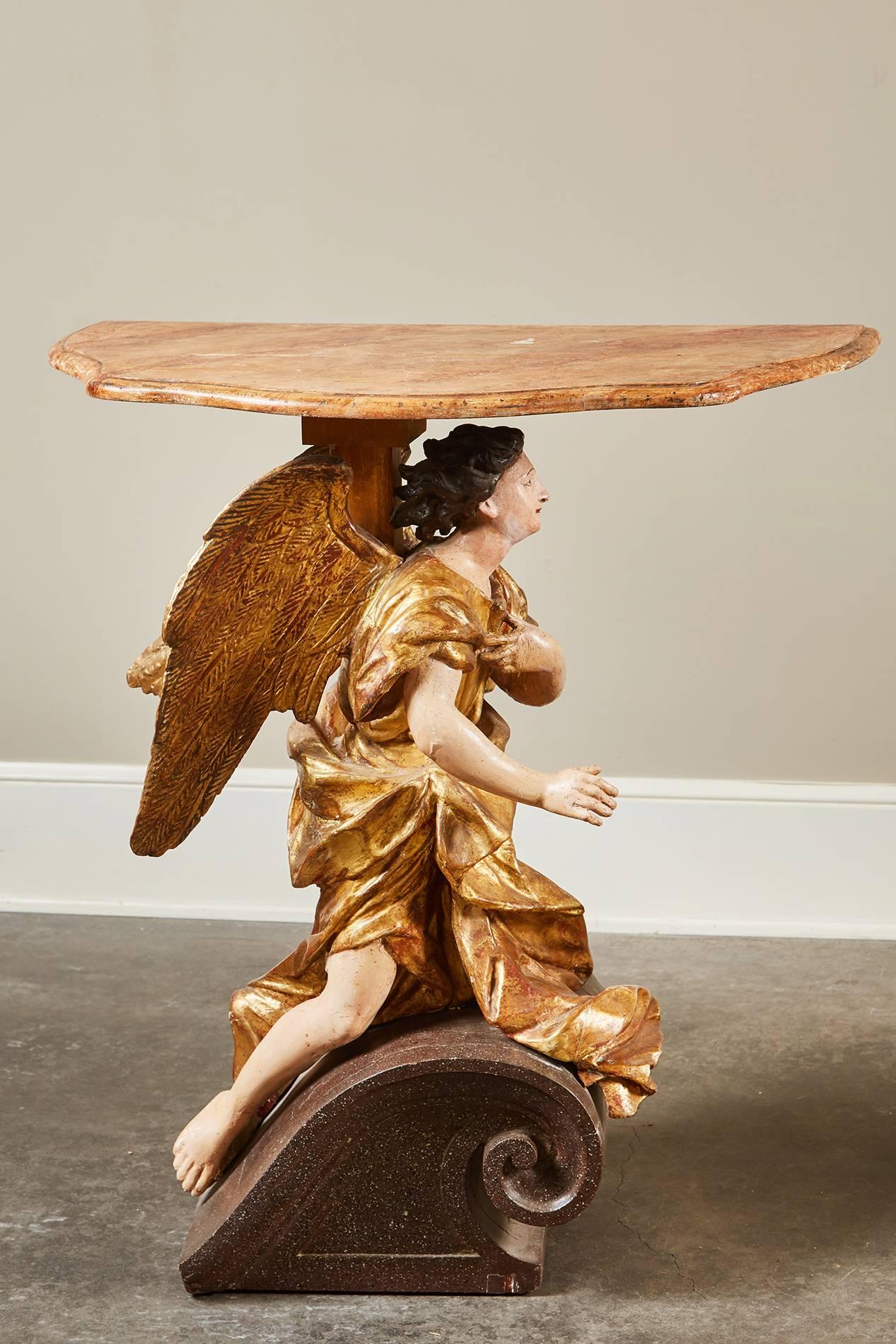 A lovely pair of 18th century Italian Baroque basilica angel tables that are comprised of gilt wood and consist of an interesting background. These angels were originally attached to a basilica wall, then adapted into tables. 