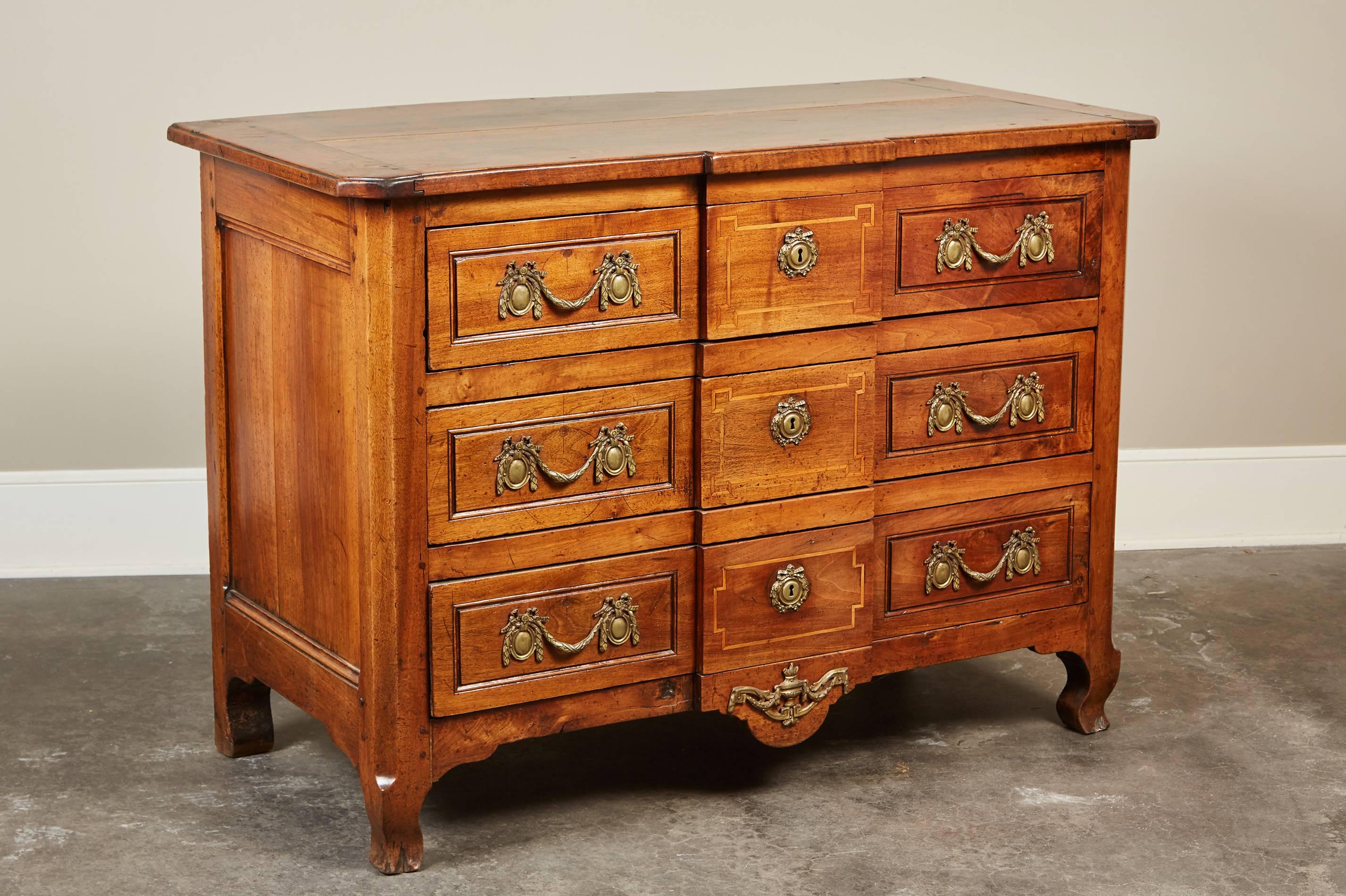A remarkable 18th century French Louis XVI walnut chest of drawers of serpentine form and features six brass garland handles and three large drawers. 