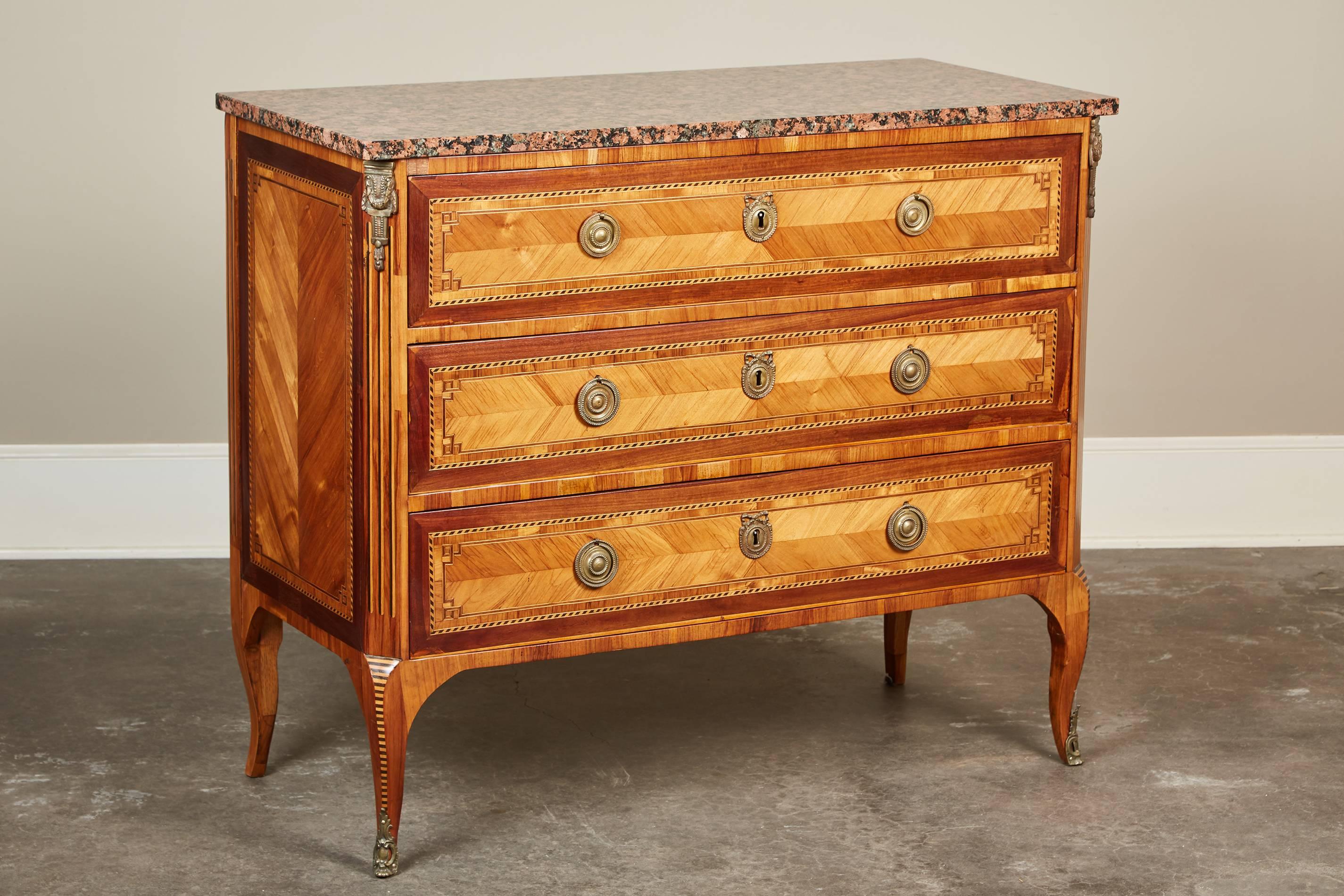 A 20th century French chest of drawers with geometric marquetry inlay and a marble top.