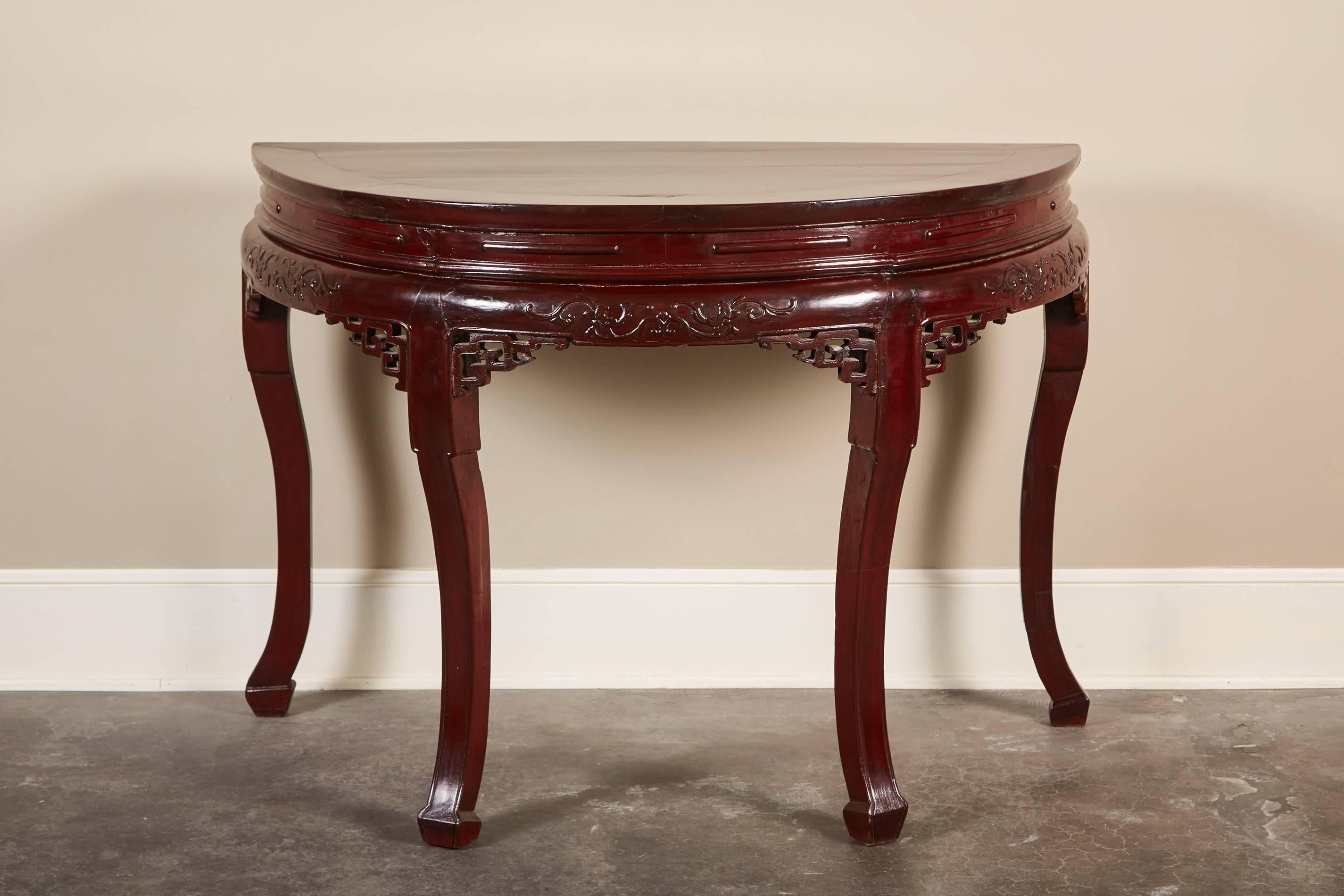 Pair of 19th century Chinese demilunes or center table of the Qing Dyansty. maroon lacquer and delicate carvings along the apron.