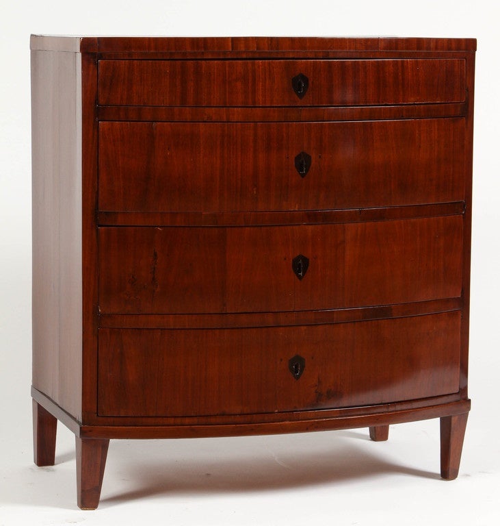 An early 19th Century four drawer dark Mahogany bowfront chest dated circa 1830. The legs are slightly narrowed at the bottom but are nonetheless straight and simple.  The keyhole hardware is of a dark metal. This 19th Century chest has beautiful