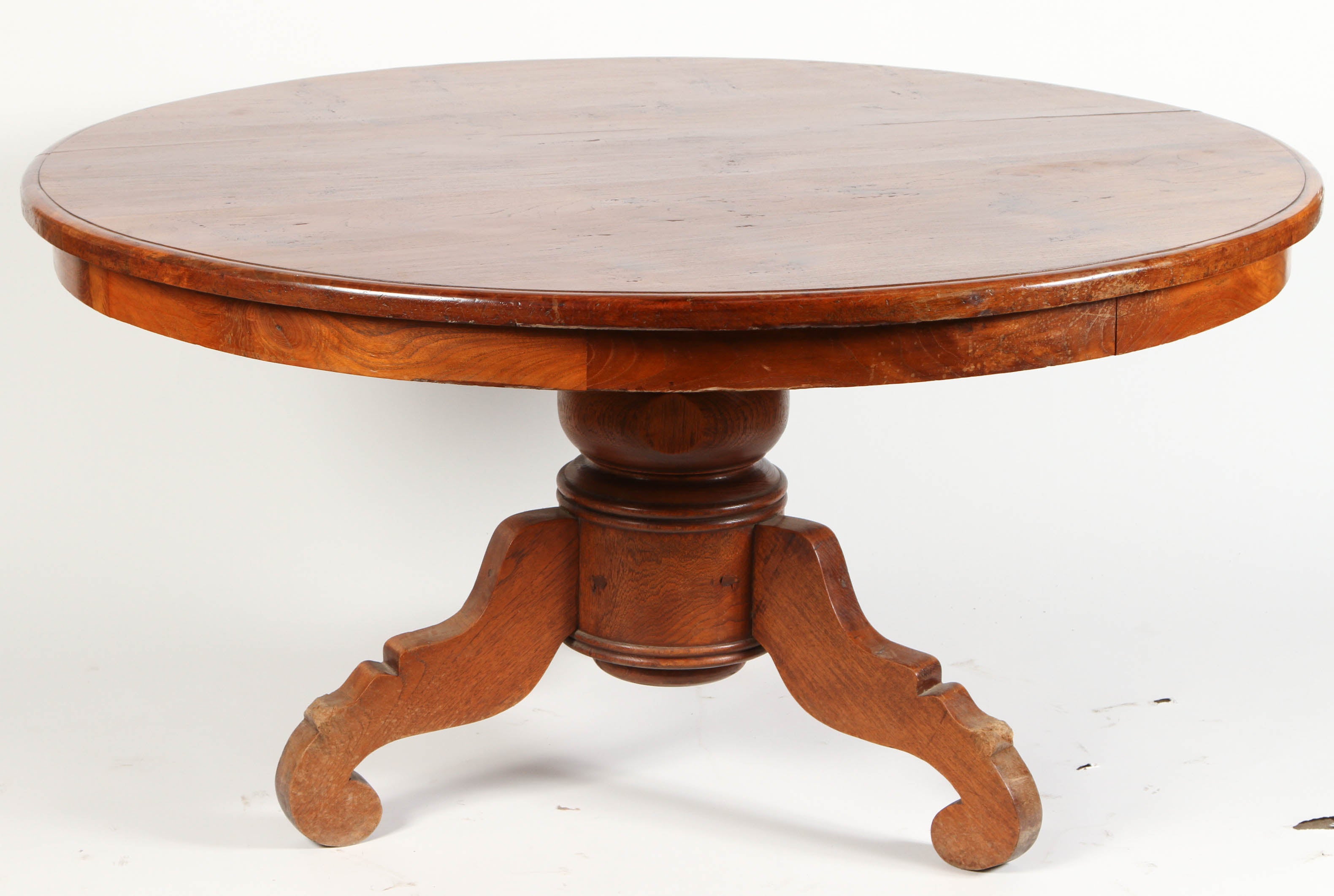 A round Indonesian teak pedestal table, circa 1920. This Indonesian table has three curved and turned legs and the pedestal is carved in both a circular and square shape.