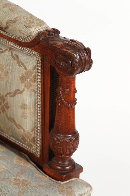 An ornately carved 1860 Louis XVI walnut arm chair from France. The chair has its original upholstery, which is in a pattern of large and small interlocking diamond shapes. The carvings are in excellent condition and are finely detailed. There is