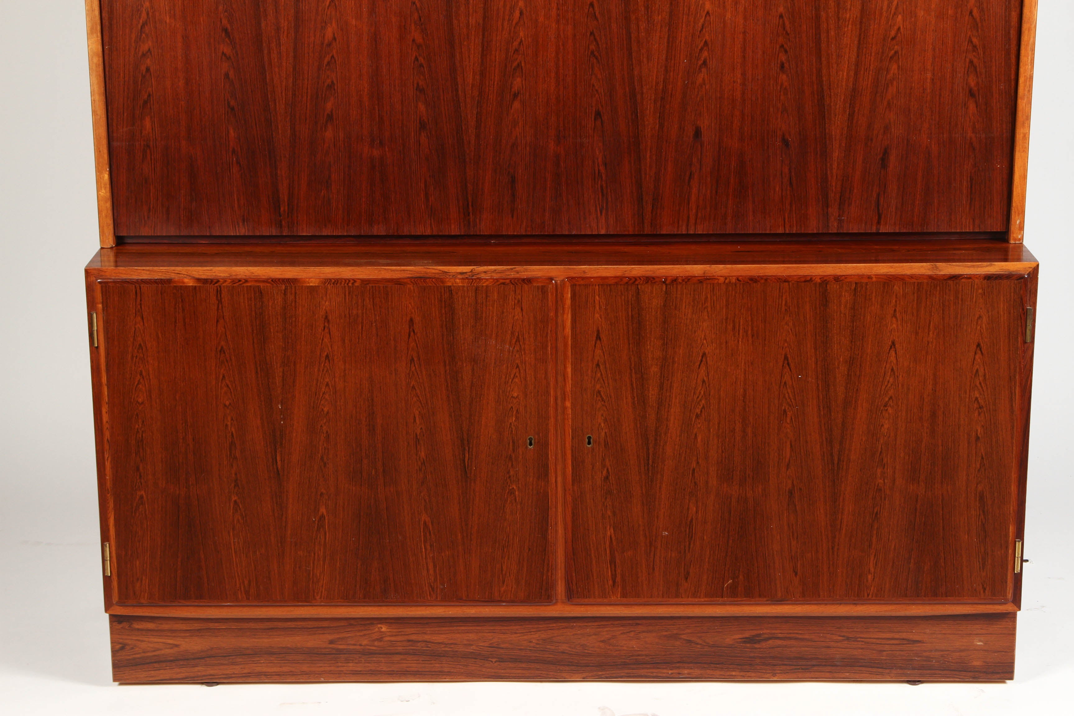 A 1970s Danish palisander rosewood desk with adjustable shelves on the inside, both below and above the working surface of the desk. The center cabinet door folds down to be the writing surface.
