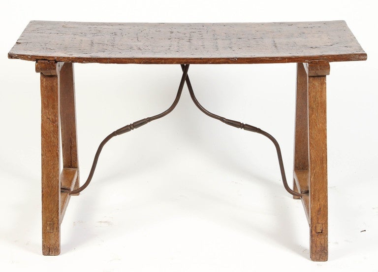 A 19th Century Spanish walnut table with an iron support.  This walnut table has a simple and straightforward design, and the support beneath it scrolls from one side to other beneath.