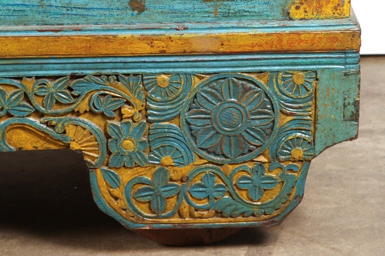 A late Victorian (Circa 1900) Indonesian wedding chest with Dutch influences, painted in turquoise and yellow. It is beautifully carved at the base in a pattern of flowers and leaves. The top of the chest is on metal hinges. Inside, there is a small