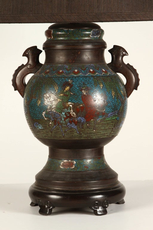A wonderful Chinese Champleve lamp, decorated with scenes of people on horseback.  The sides have handles which appear to depict an archaic dragon. Sold with custom black shade.