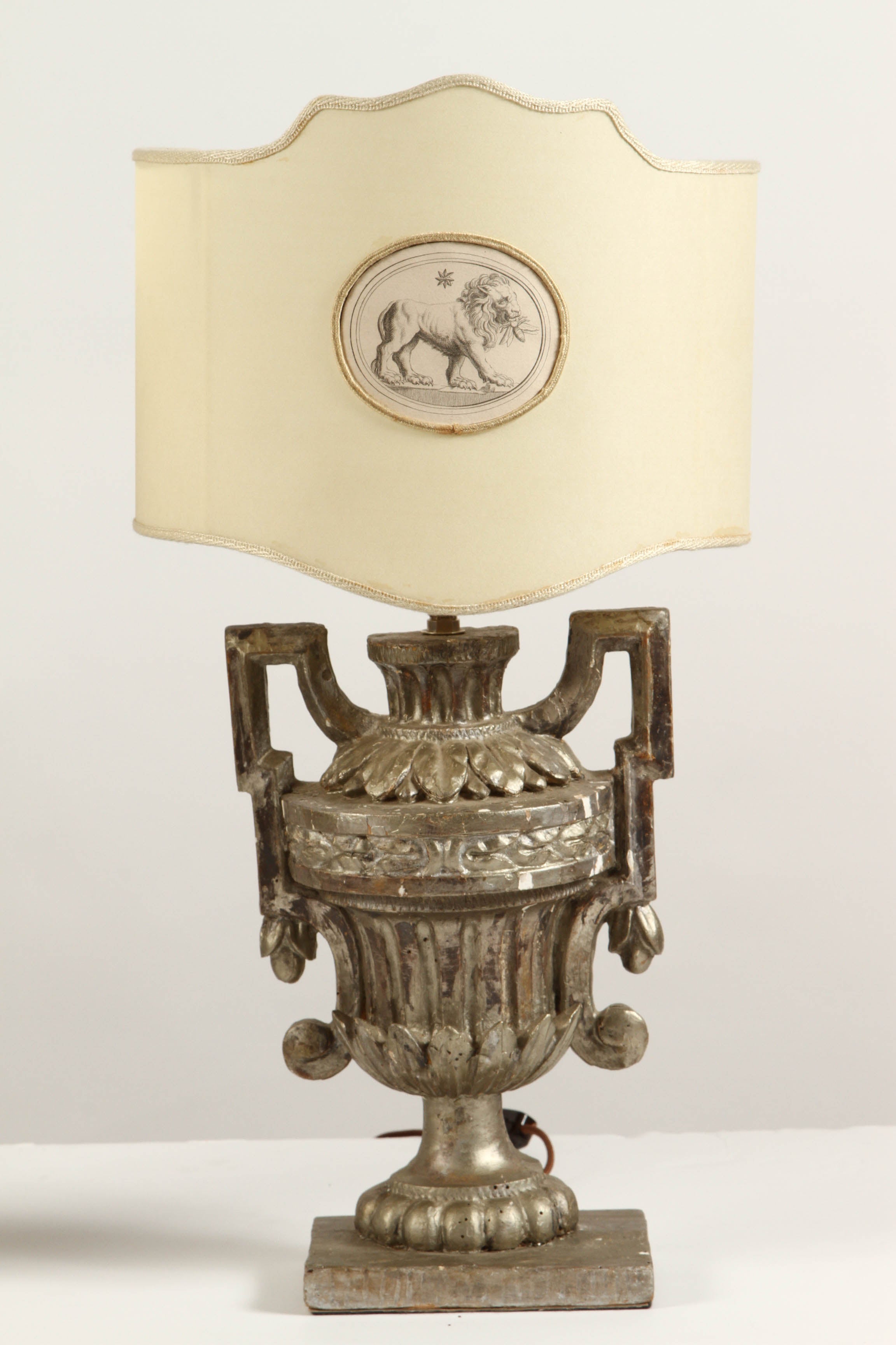 A pair of Italian lamps, dated as 18th Century, offered here with oval Florentine paper shades which are open in the back. The main body of each of these lamps is in the shape of an elaborately shaped and decorated urn with handles on each side for