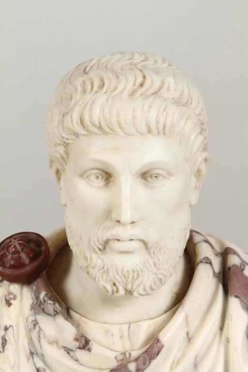 An early 20th Century Italian marble bust of a distinguished gentleman, perhaps a Roman senator.  The marble from which this portrait bust is made is a cream color with streaks of brown and dark grey, and the base is also marble, in light brown.