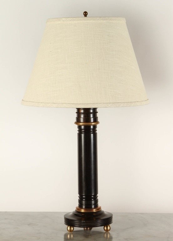 A pair of 20th Century column lamps in Solid Ebony, with brass detail, and with three small brass ball shaped feet for each lamp.  Sold without shades.