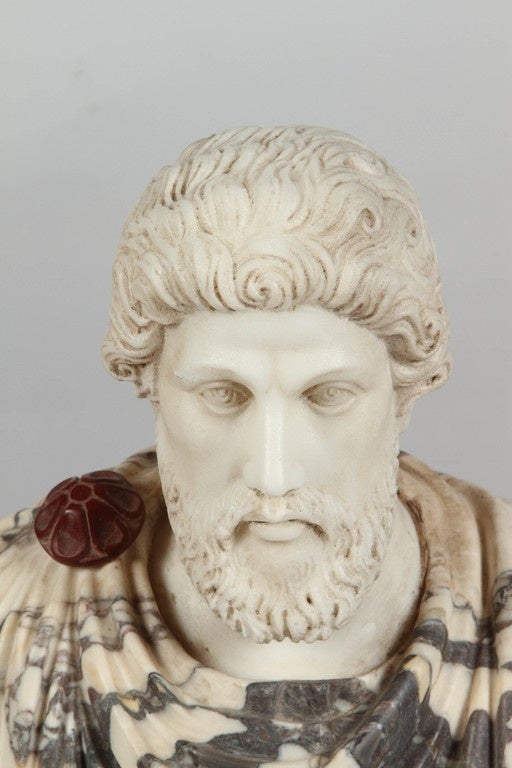 An early 20th Century Italian reproduction marble bust of what looks like a distinguished Roman gentleman clad in a toga. Perhaps a senator? He sits on a base of medium brown, grey and black streaked marble.