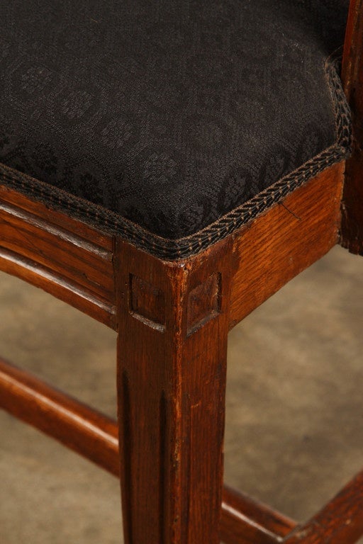A late 18th Century Danish armchair in elm wood, with its seat upholstered in a dark colored fabric.  There are flower and leaf motifs carved into the frame at the top and midway down the back. The seat, back and arms of this elm wood armchair have