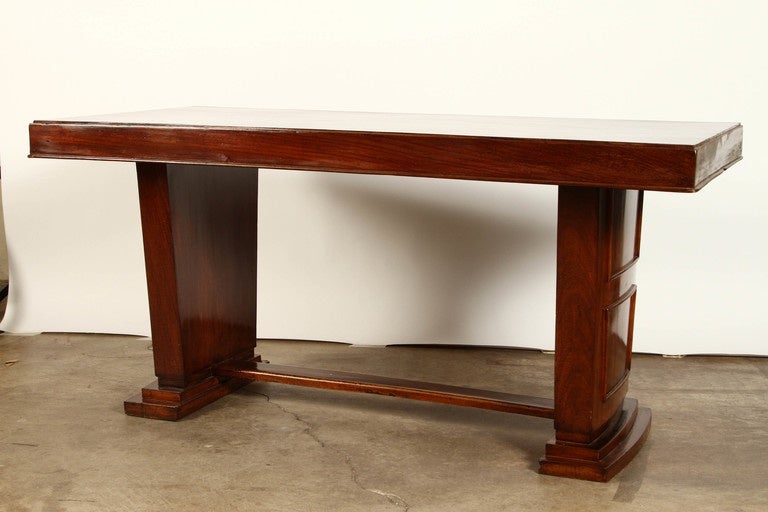 An Art Deco Rosewood French Colonial desk, created circa 1930.  This Art Deco desk in rich colored rosewood, with solid burlwood top, has simple yet elegant geometric patterns in the moulded pattern on the bases and on the table top.