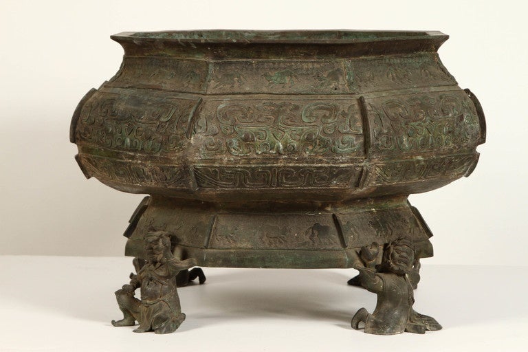 A 19th Century Chinese Bronze Jardiniere with feet shaped like Chinese warriors. The outside surface is covered with illustrations of animals and different decorative shapes.